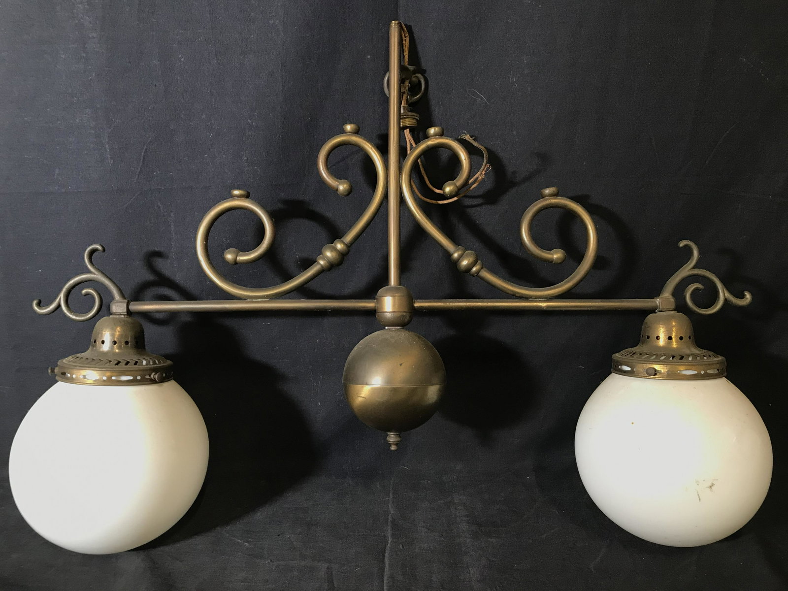 Vintage Brass Chandelier Fixture: Chandelier is vintage possibly antique. Piece is brass. Contains 2 white toned globe shaped bulbs. Piece has c curve structures near center. Piece measures approximately 22 inches tall 27 inches wide 
