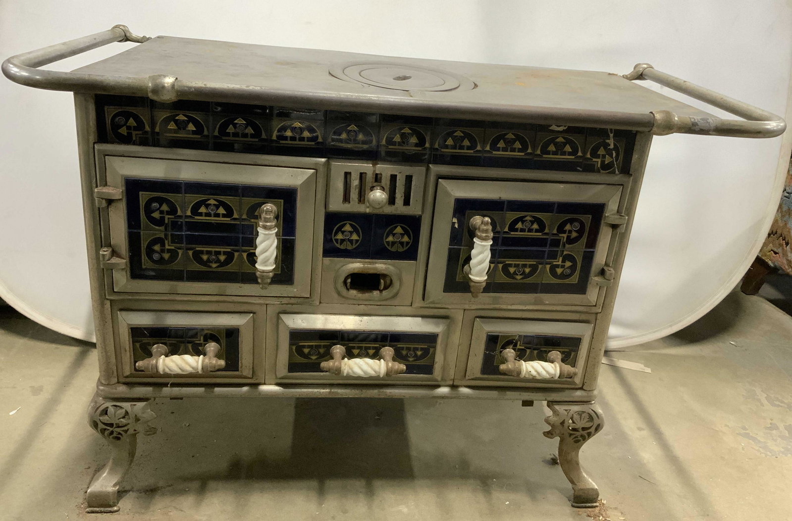 Antique Footed Victorian Cast Iron Porcelain Stove: Stove is antique. Piece has railing at top. Stove also has center cooktop. Piece Art Deco design & etched metal feet with pierced leaf detail. Sides of stove have cobalt blue porcelain tile with gold 