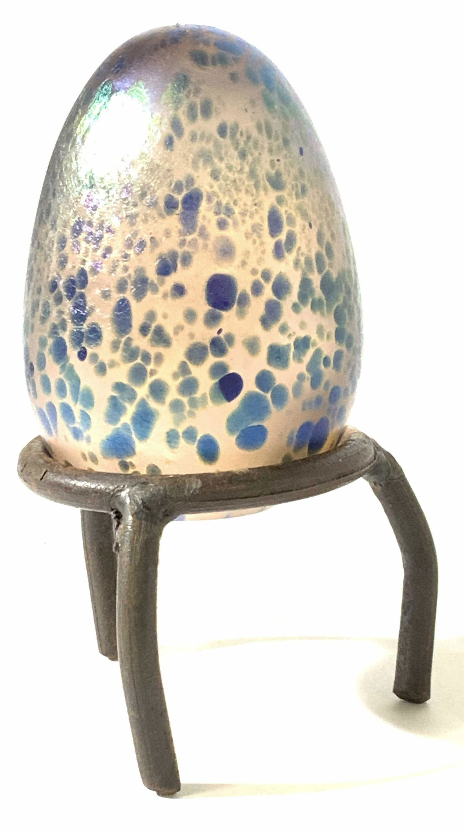 Signed ORIENT & FLUME Glass Paperweight on Stand: Hallmarked Studio Art. Signed by hand, Orient and Flume American studio art glass paperweight, iridescent coating, speckled design, glass egg fits in metal footed stand. Reads Orient & Flume- D.G.X.C.