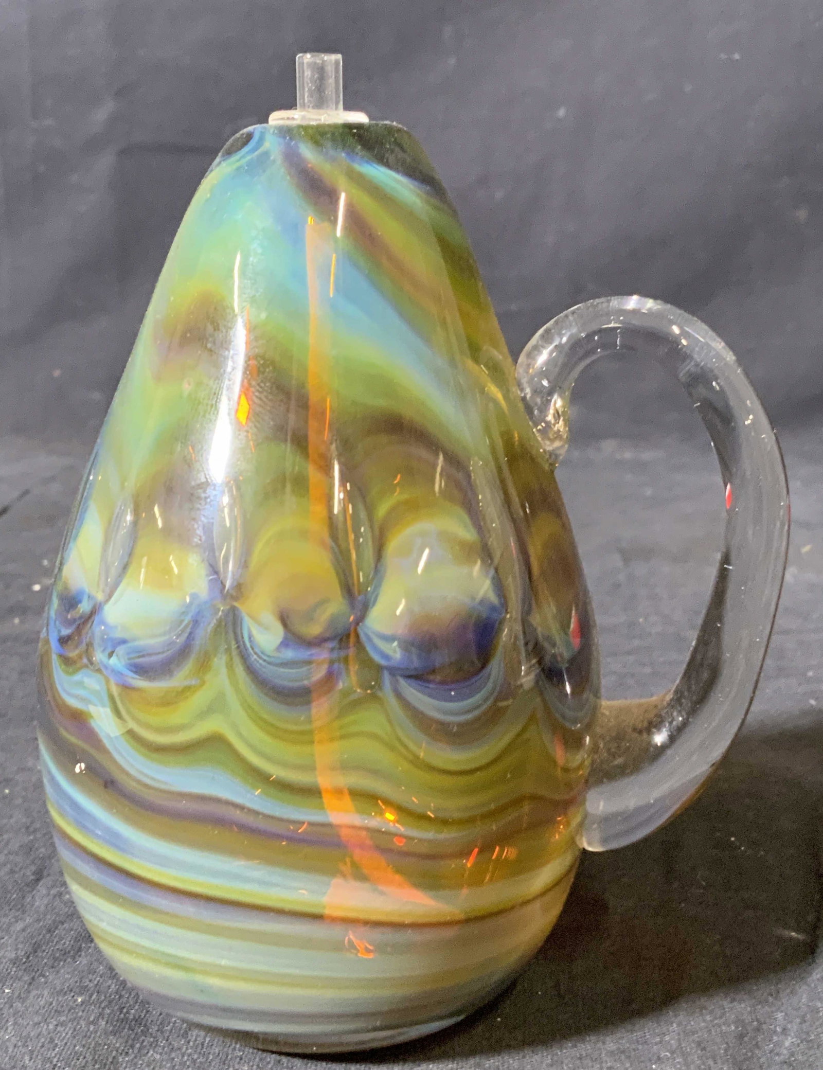 Signed Art Glass Pear Shaped Candle Burner: Underside is signed illegibly. Candle burner is hand crafted. Piece has glass topper with string wick. Burner is pear shaped with handle. Piece measures approx 5.5 inches tall 4 inches wide. Property 