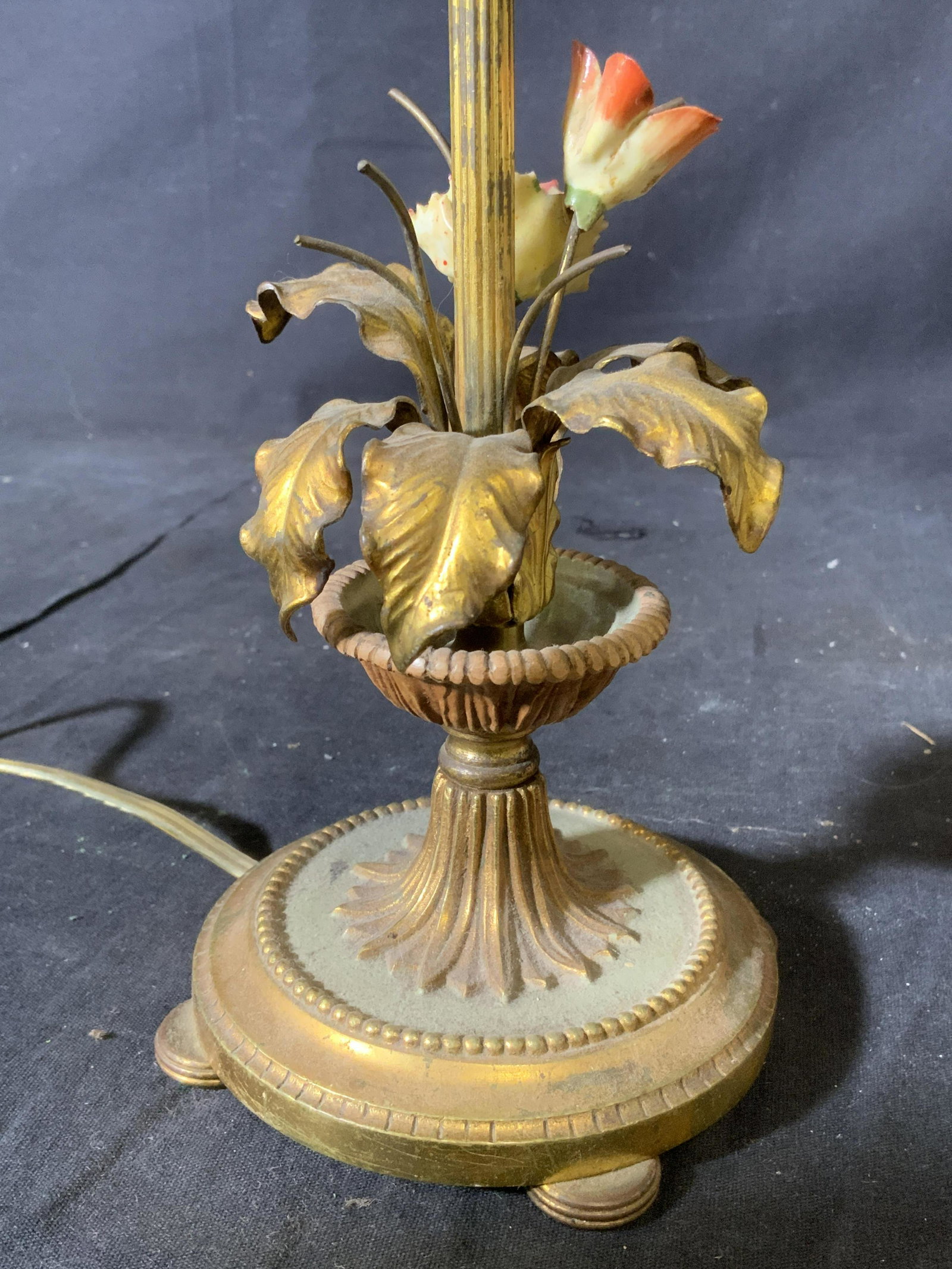 Vintage Gilt Metal Brass & Tole French Lamp: Lamp is vintage possibly antique. Piece has brass base, floral and leaf detail appear to be gilt metal and tole. Lamp appears to be French. Base is footed. Piece measures approx 14 inches tall 4 inche