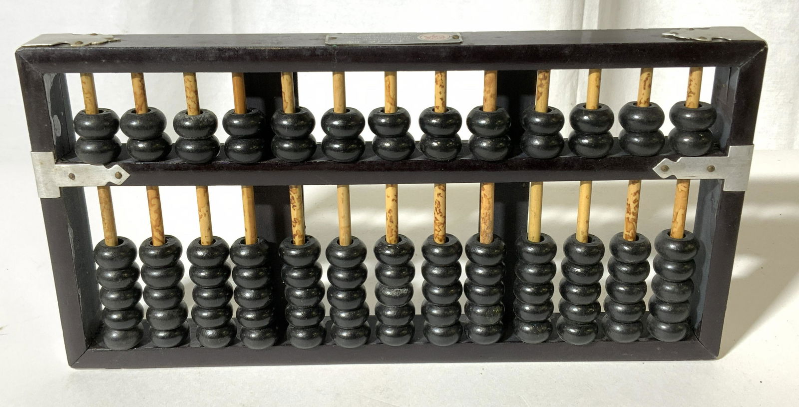 Vintage LOTUS FLOWER BRAND Abacus: Vintage Wooden abacus. Crafted from wood, and metal straps, straps are secured to the abacus through nails. The label is metal, and reads LOTUS FLOWER BRAND, MADE IN THE PEOPLES REPUBLIC OF CHINA. Mea