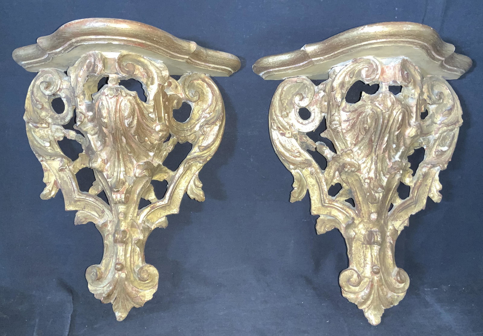 Pr-GRAND Antique Gilt Carved Wood French Sconces: Carved in the French Baroque style, this pair of antique gold leaf wall sconce shelves has intricate hand formed carvings, red tones visible through gold leaf, flat scalloped top shelf. App 14 in. L, 