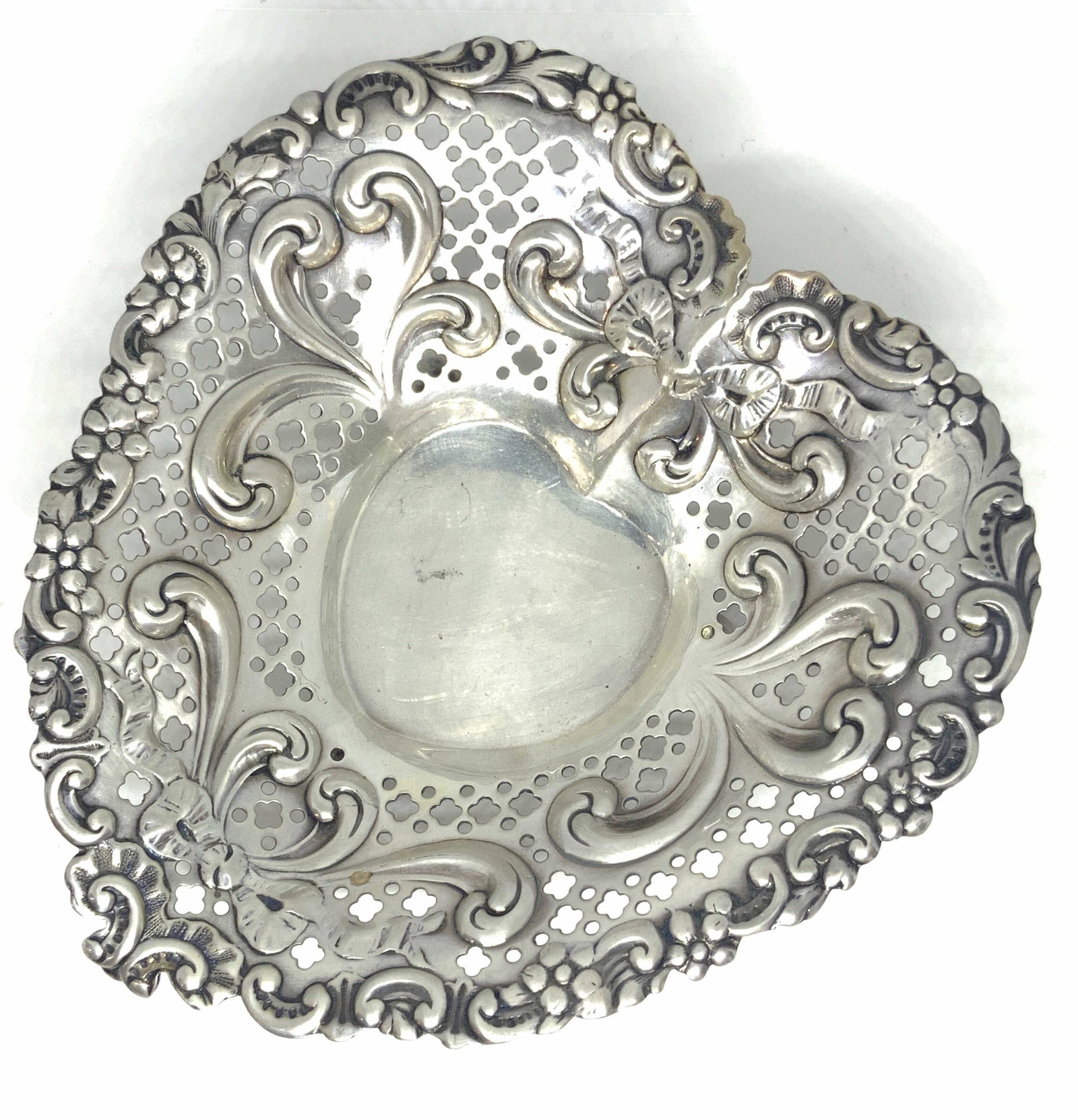 GORHAM Signed Vintage Sterling Heart Form Bowl: A vintage heart form bowl with embossed and pierced metalwork designs. Florals trim the rims and a delicate embossed bow adorns the center. The interior is polished smooth. The underside possesses thr