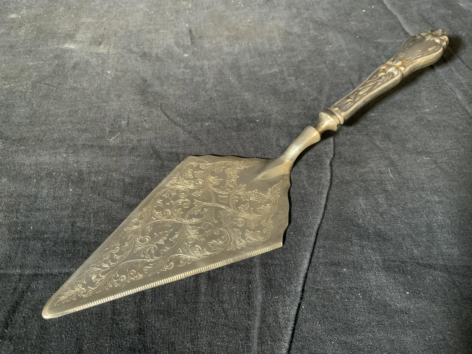 Kent Silversmith Cake Knife Server: Kent Silversmith serving knife, text to backside of knife reads ‘Kent Silversmith’, subject a serving knife with vine like designs to the surface, piece measures 11.75 inches in length and weighs 