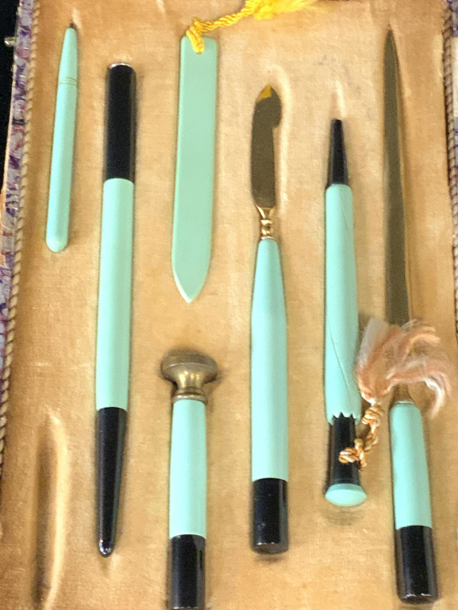 7pc Vintage Art Deco Boxed Desk Set: A colorful, shatter style design case containing desk tools. The exterior of the case is comprised of purple and pink hues. It secures with metal snap closure hardware. The interior features satin and