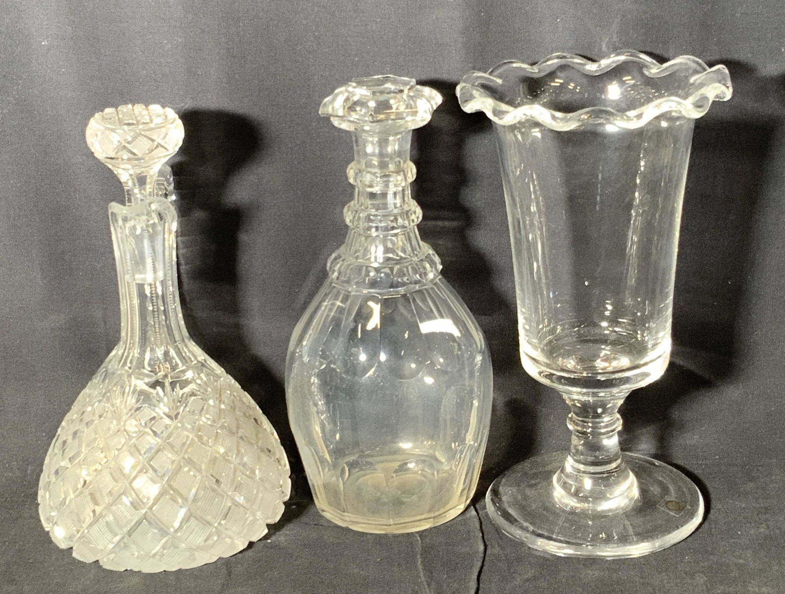 Lot 3 Vntg Clear Art Glass Tableware Accessories: Three colorless clear glass tableware accessories. Two are glass decanters, each has a glass stopper. One piece is comprised of cut and etched glass, while the other one has embossed glass accents alo