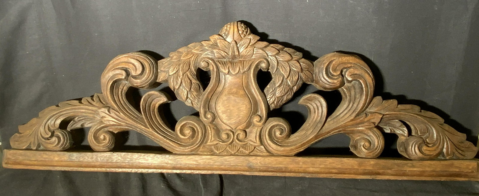 Antique Hand Carved Wooden Wall Art Plaque: An antique deep, rich brown carved wood wall art piece. Carved nature motifs, such as leaves, along abstract swirls. Underside has hardware for hanging. Can be displayed on a wall, over a door, in an 