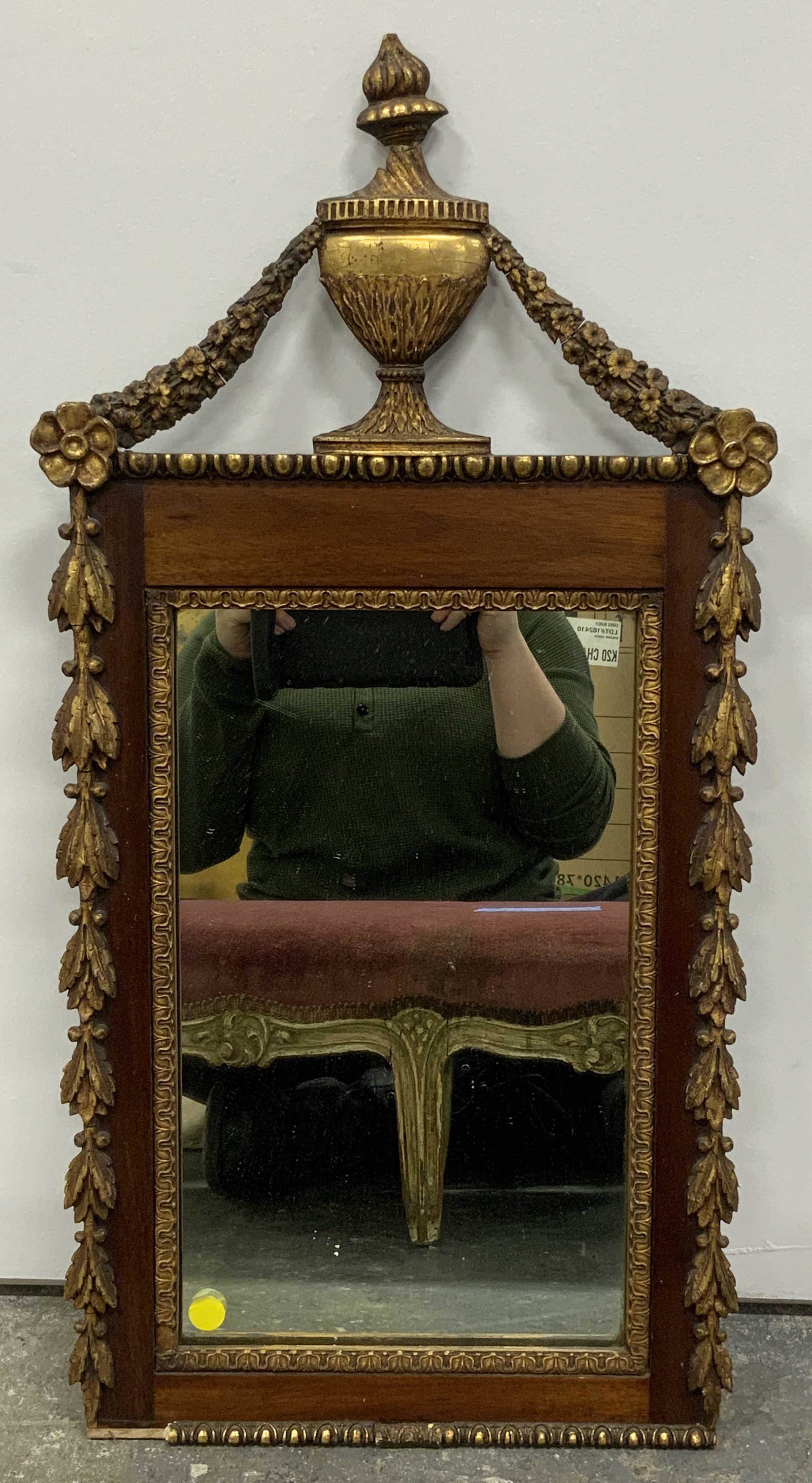Antique Gilt Wood Wall Mirror: Antique gilt wood wall mirror, no apparent inscriptions or markings, subject a dark wood framed mirror with gilt wood acanthus leaf accents, top of frame features a lidded vase also in gilt wood, some