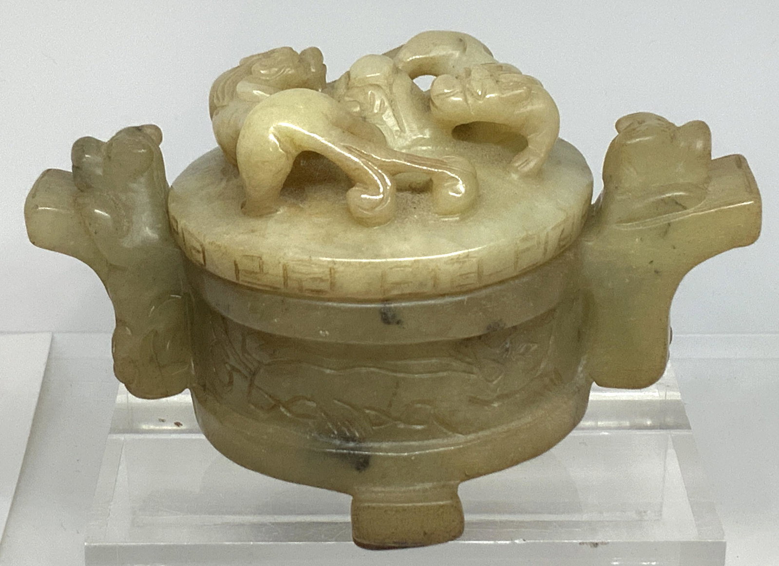 Elaborate Carved Mottled Jade Foo Dog Trinket Box: Hand carved Asian mottled jadeite lidded trinket box. This piece features intricate openwork on lid with two territorial guardian temple dogs in relief. Additional In relief Fu carvings as handles. Th