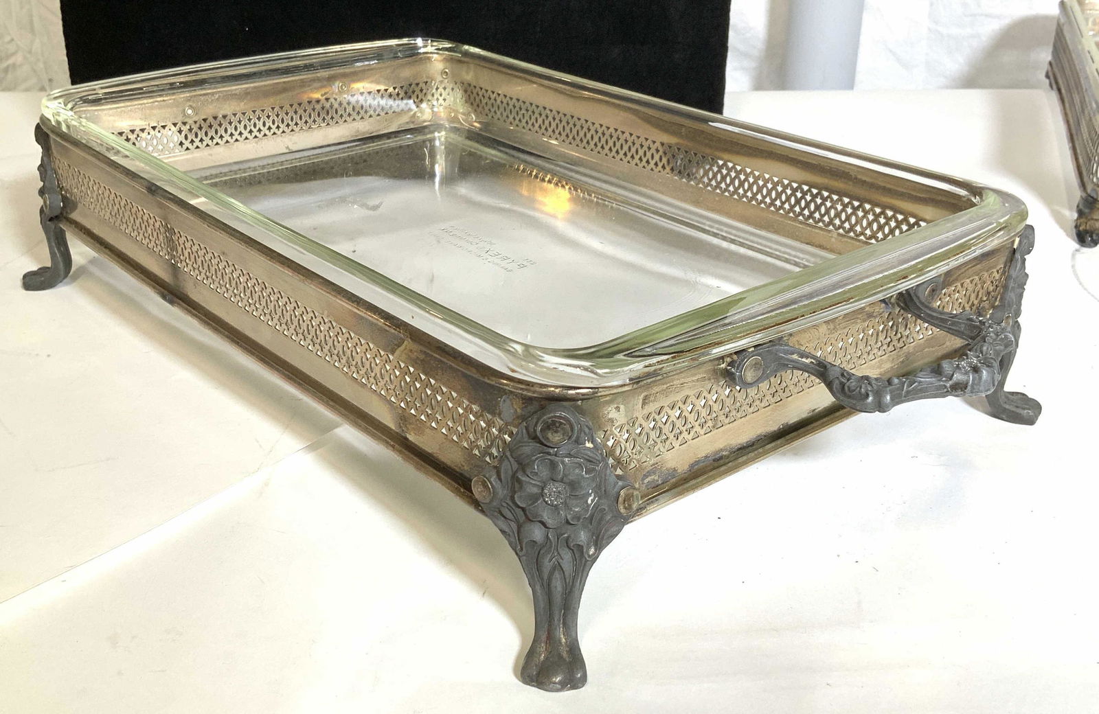 Pair Footed Silver Plated Buffet Stands w Pyrex: Pair of art nouveau silver plated buffet stands, strong carry handles. Claw feet. Measures 19 in. Long with handles. Both come with Pyrex Bakeware that is also microwave safe. Dish measures 13.5 x 8 3