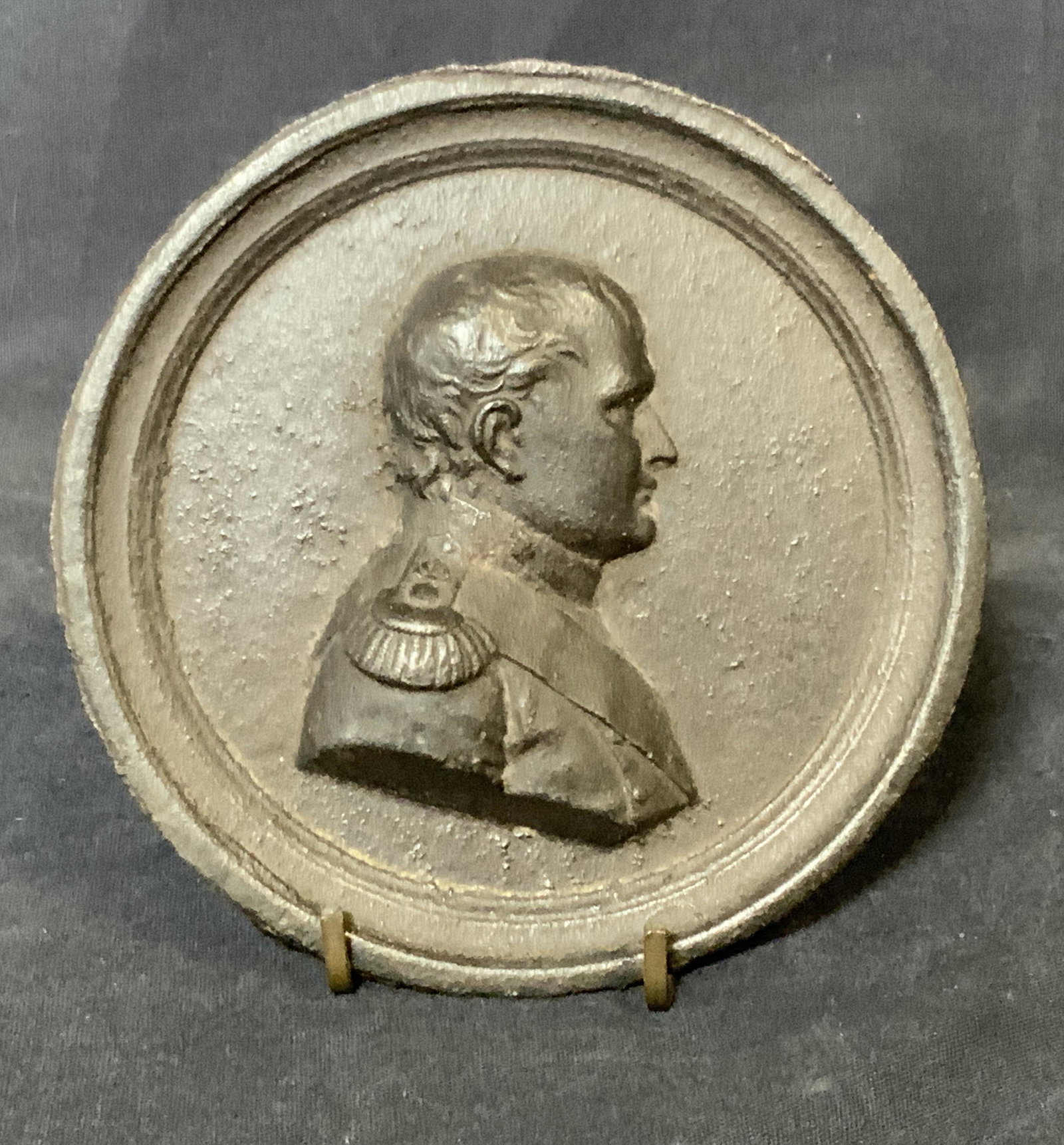 Bronze Relief Portrait Plaque of Napoleon: Bronze relief portrait of Napoleon, no apparent inscriptions or signatures, subject a side profiled portrait of the historical figure Napoleon, piece is in a circular shape being propped up by accompa