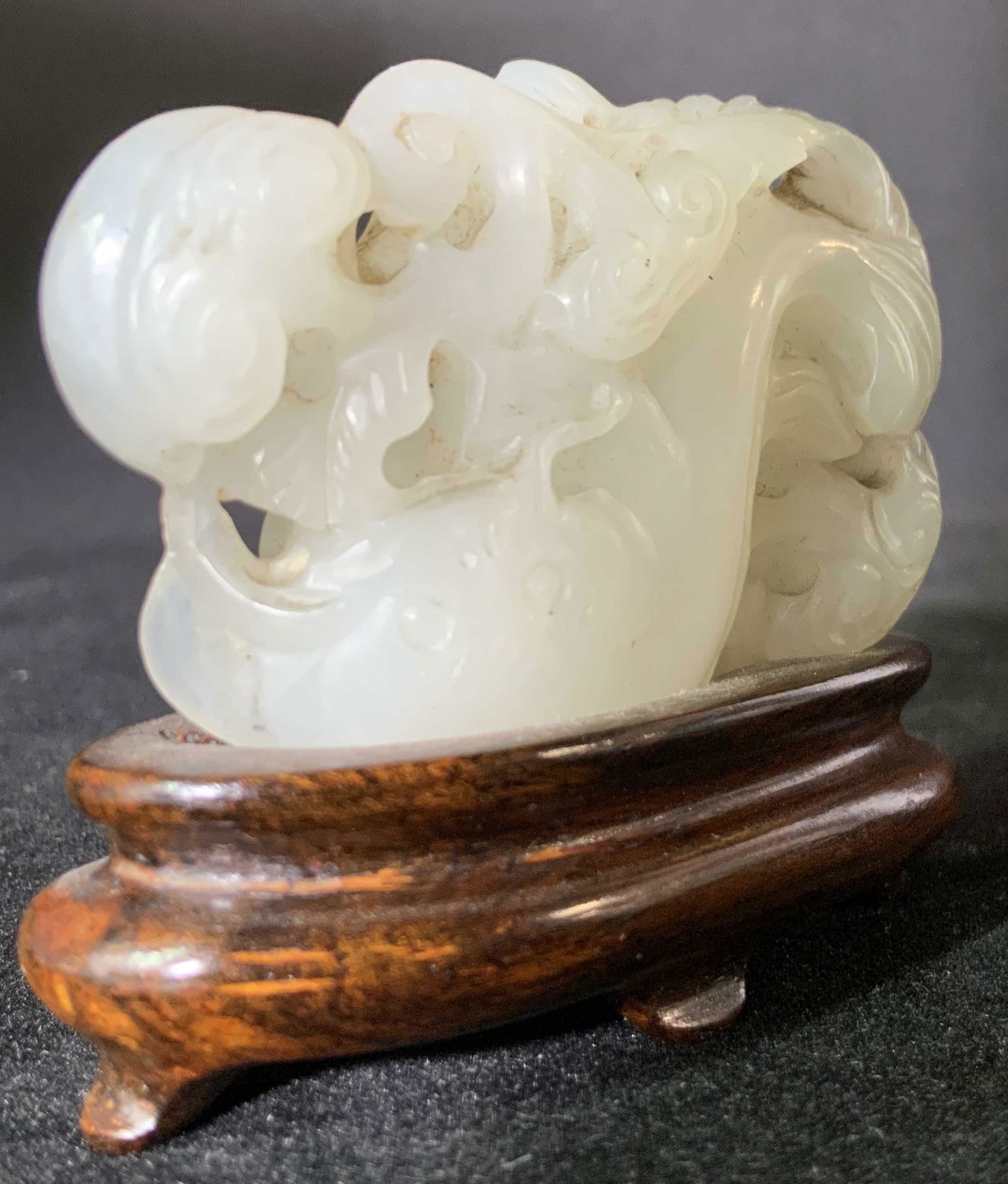 Antique Hand Carved WHITE JADE FISH W/ Stand: An antique hand carved white jade fish form set onto a hand carved wooden stand. The wooden stand is a rich brown color and possesses four feet. The piece is intricately incised and detailed. The form