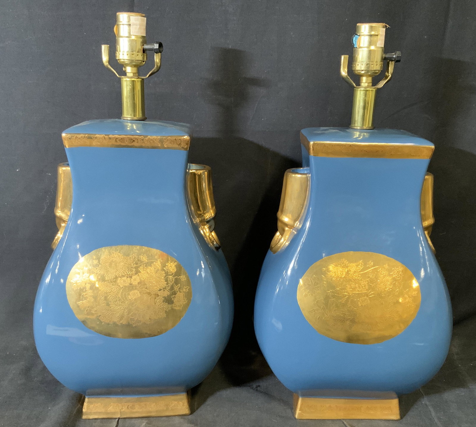 Pair Porcelain Blue & Gold toned Lamps: Pair Porcelain Blue and Gold lamps, no apparent inscriptions or stamps, subject two lamps, painted blue and gold, lamps in the shape of vases, front emblem to lamps displays a floral design, both lamp