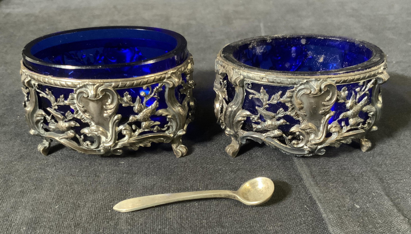 Pair Sterling Silver Salt Cellars W Cobalt Glass: Pair Vintage Marked Sterling Silver and Cobalt Glass Salt Cellars with two spoons, inscription to spoons read ‘T & Co STG M’, both measure 1 1/2 inches tall x 2 5/8 inches at widest point, spoons 