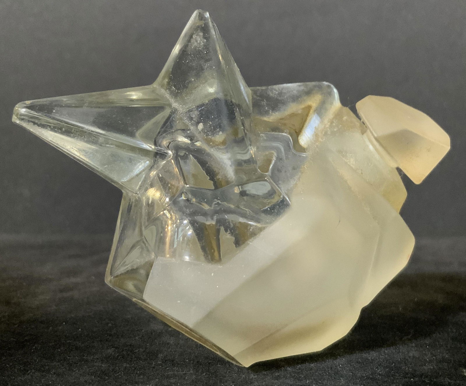 THIERRY MUGLAR ANGEL PERFUME Art glass Bottle 2002: Thierry Muglar Angel Perfume. The bottle depicts a star being cut out of a solid rock crystal. Comprised of colorless clear glass and frosted glass. The fitted cap is a part of the rock crystal. A Sta