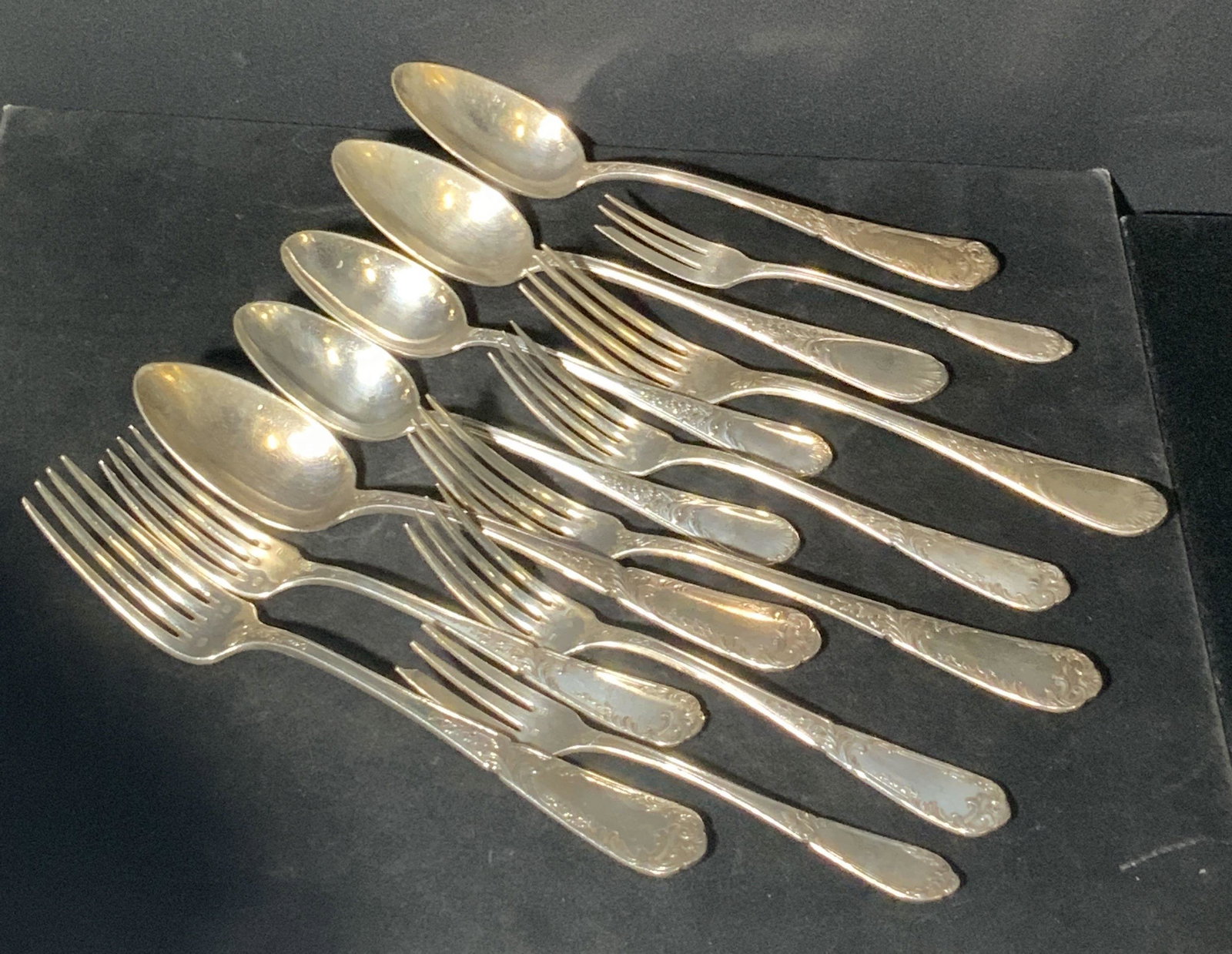 Lot 13 Antique French Silver Plated Utensils: Circa 1900-1920s antique spoons and forks crafted by various French makers. Thirteen in total. All utensils silver plated. Pieces all feature etched & embossed designs along the handles. Some designs 