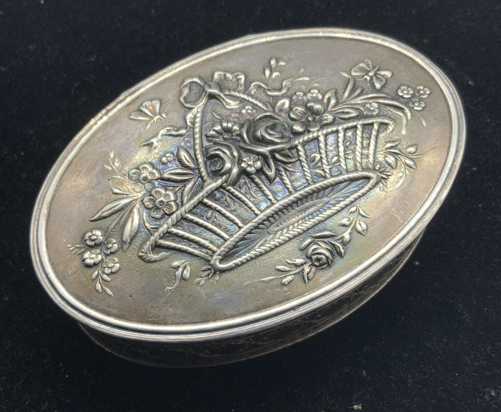 Antique Victorian Sterling Silver French Pill Box: An antique sterling silver hinged pill box. The lid and base fit together seamlessly. Polished silver exterior with etched & embossed details on the lid and base. Designs depict flowers, baskets, ribb