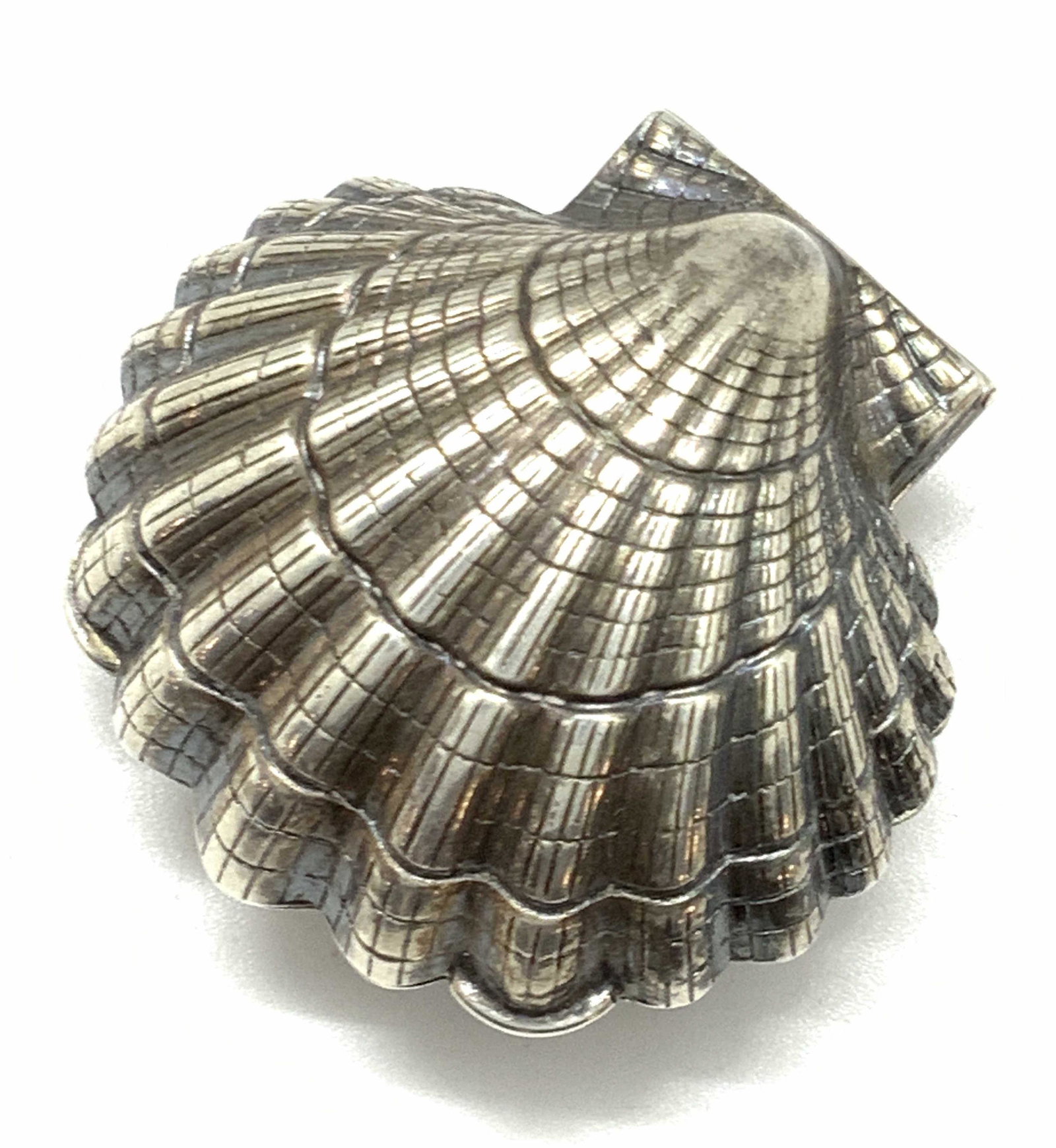Vintage Sterling Silver Shell Form Pill Box: A vintage sterling silver shell for pill box. The piece has etched designs that mimic the natural appearance of a shell. The lid and base fit together seamlessly. A gold wash covers the interior. The 