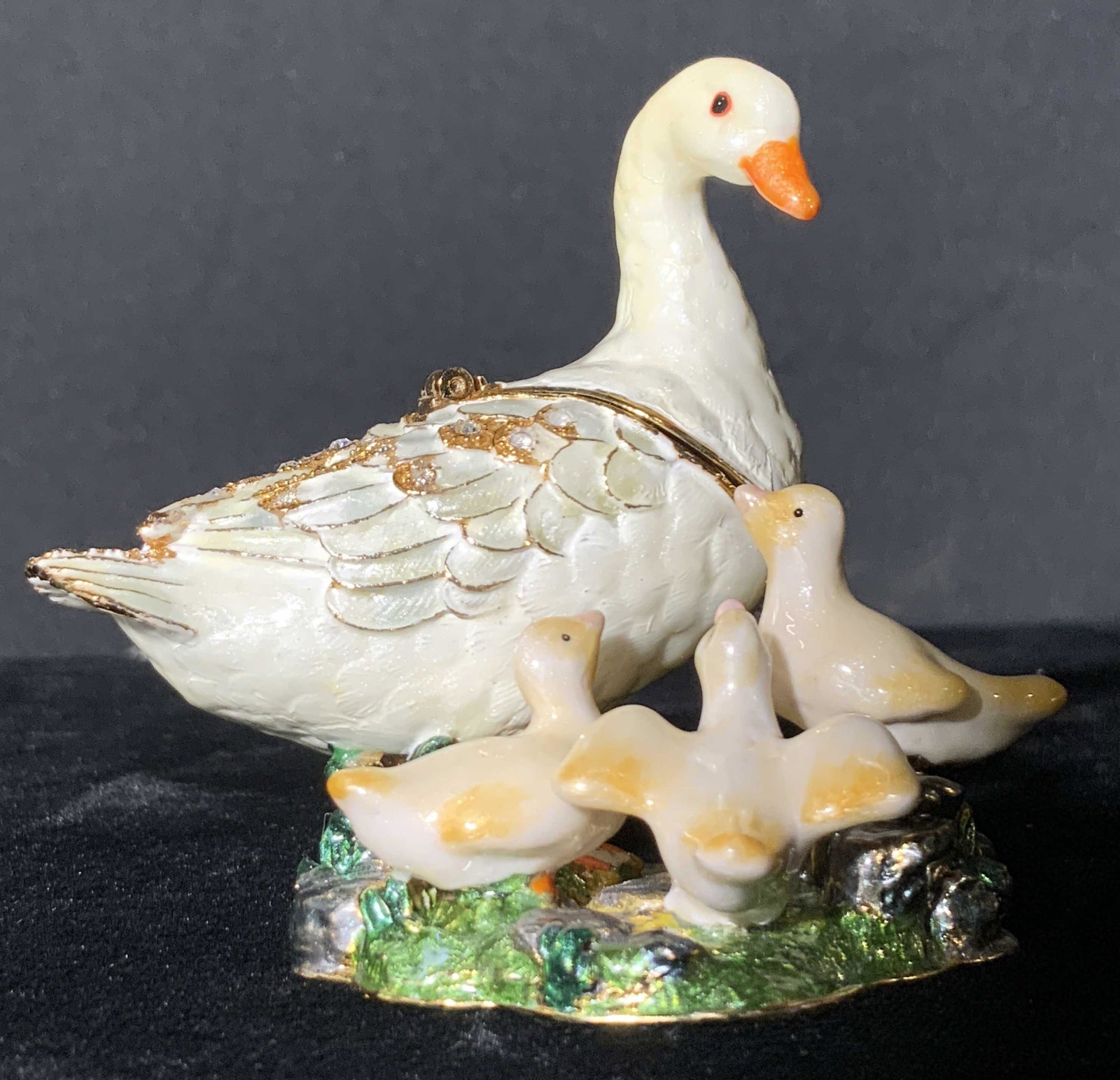 NOBILITY Enamel White Geese Trinket Box, Org Box: A Nobility Brand trinket box in the form of a mother goose standing atop a green mound with her three chicks. This piece comes with it’s original box that reads NOBILITY across all sides. The box co