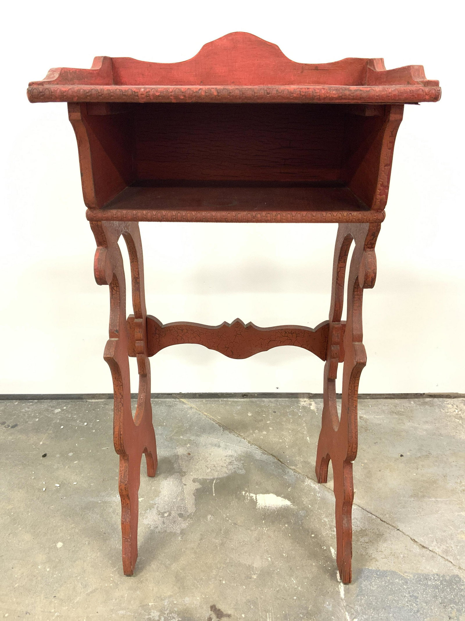 Antique Carved Wooden Wash Stand: Wash stand is vintage possibly antique. Piece is red toned & wooden. Stand contains 2 carved wooden legs with stretcher on on backside. Tabletop has storage pocket underneath. Piece measures approx 32
