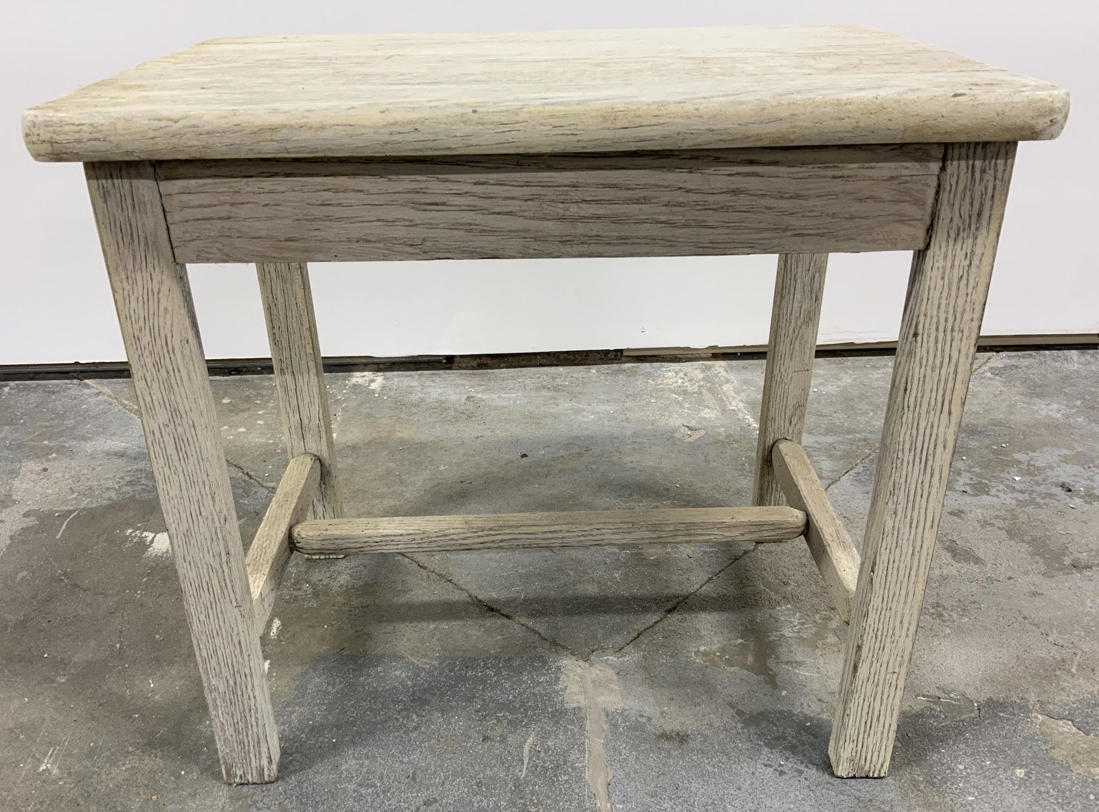 Vintage Off White Wooden 4 Leg Bench: Bench is wooden. Piece is vintage possibly antique. Piece has 4 legs with Stretchers in between. Off white in color. Wood grain visible. Piece measures approx 16 inches tall 18 inches wide 12 inches d
