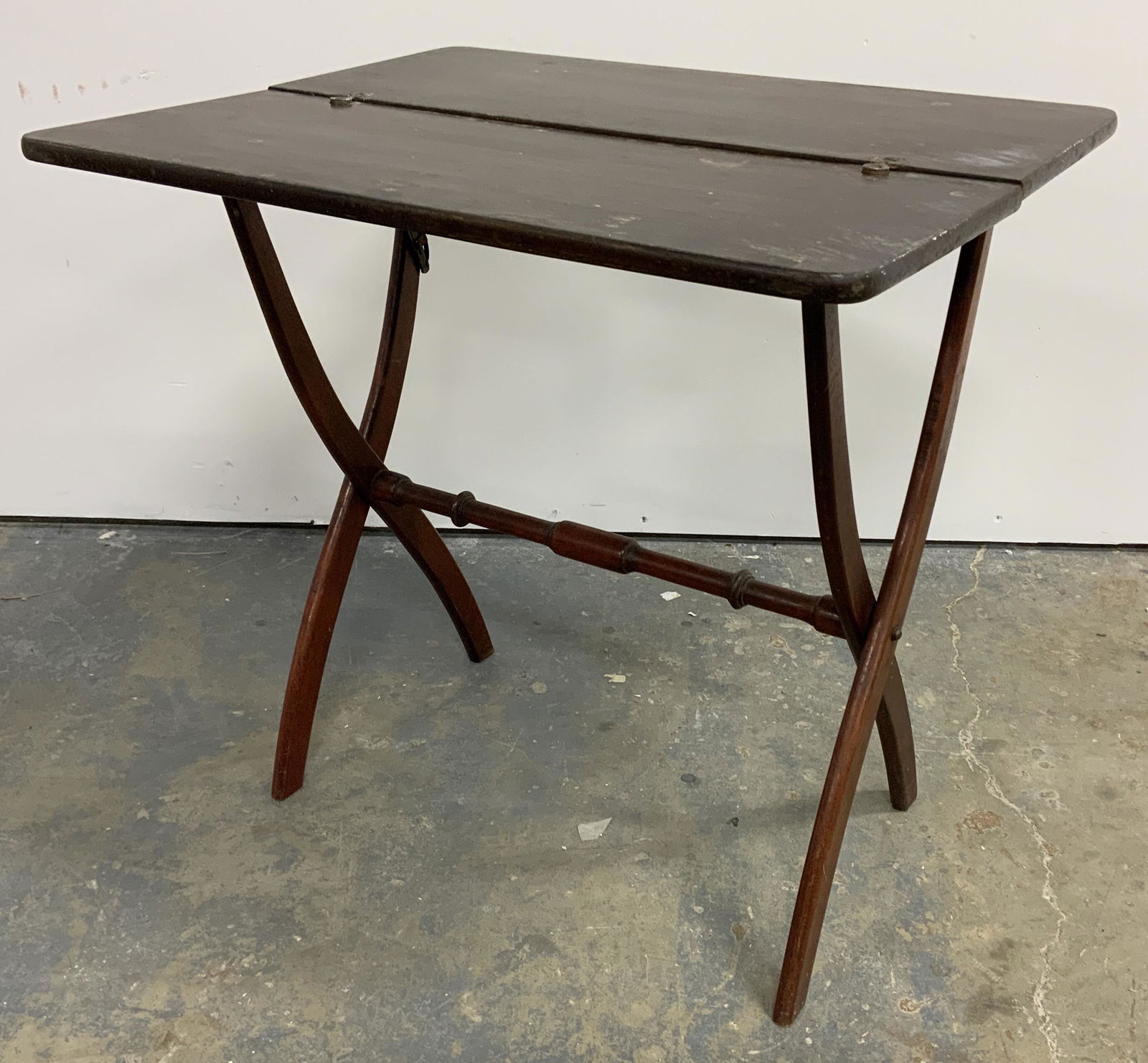 Vintage Folding Wooden Tray Table: Vintage, possibly antique, collapsible tray table. Tabletop splits in half and folds, two halves are secured by a metal clasp when the table is in an upright position. Measures approx 23 inches H, 24