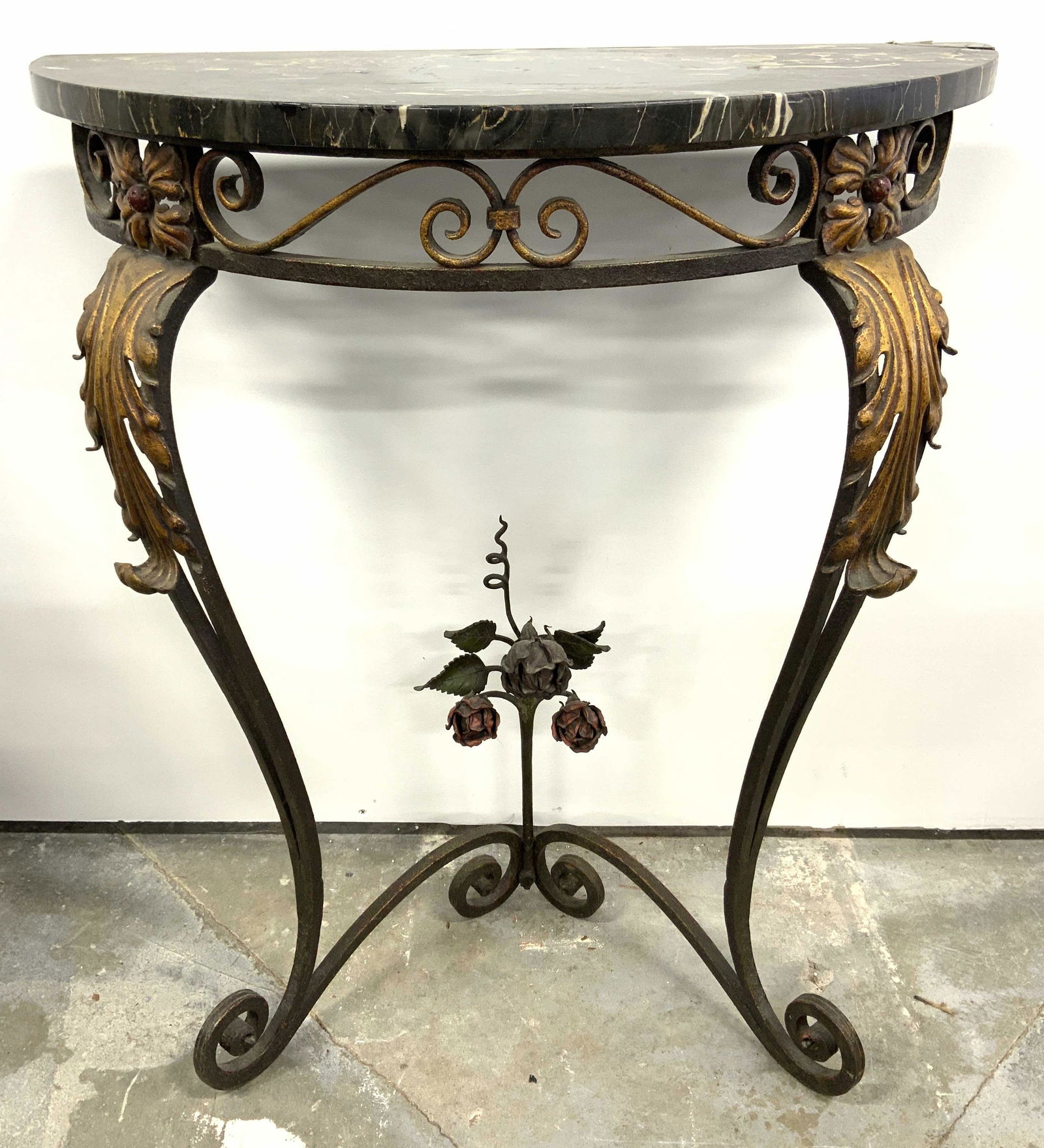 Vintage Marble Top Half Moon Console Table: Console table is vintage possibly antique. Piece has black toned marble top with half moon shape. Table has s scroll structures, & multi toned floral & leaf structures. Piece measures approx 31 inches