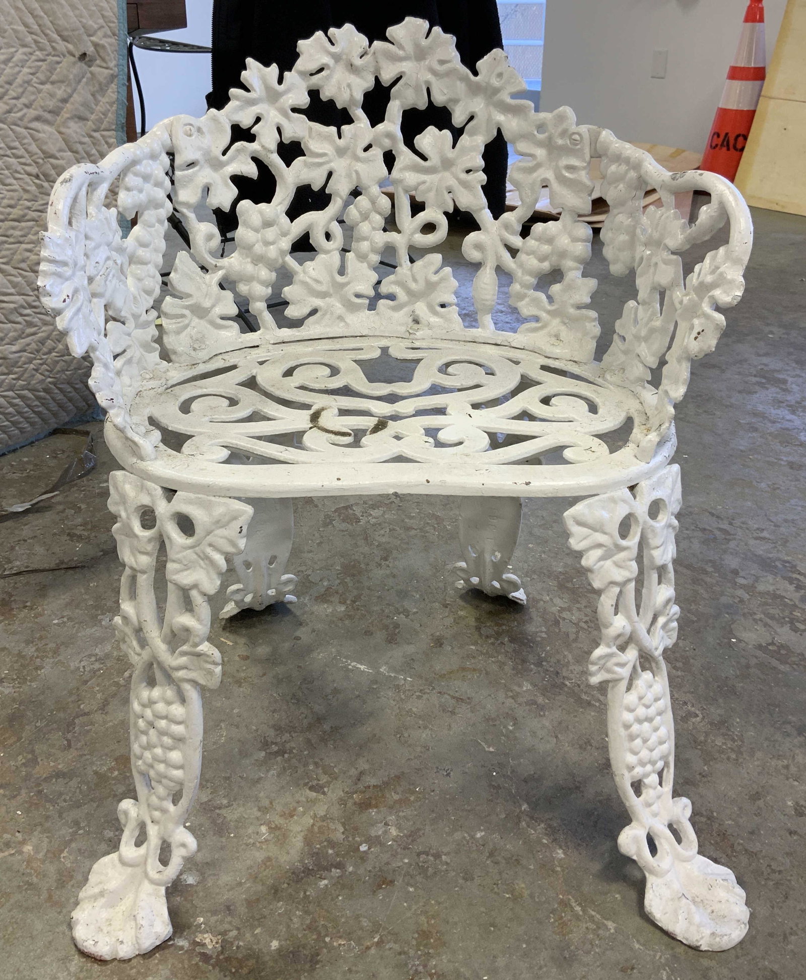 Vintage Outdoor Iron Arm Chair: Antique iron chair, possibly white iron. Grapevine patterns are cast into the chair. Painted white, appears to be hand painted. Measures approx 28 inches H, 23 inches W, and 22 inches deep. Wear is co