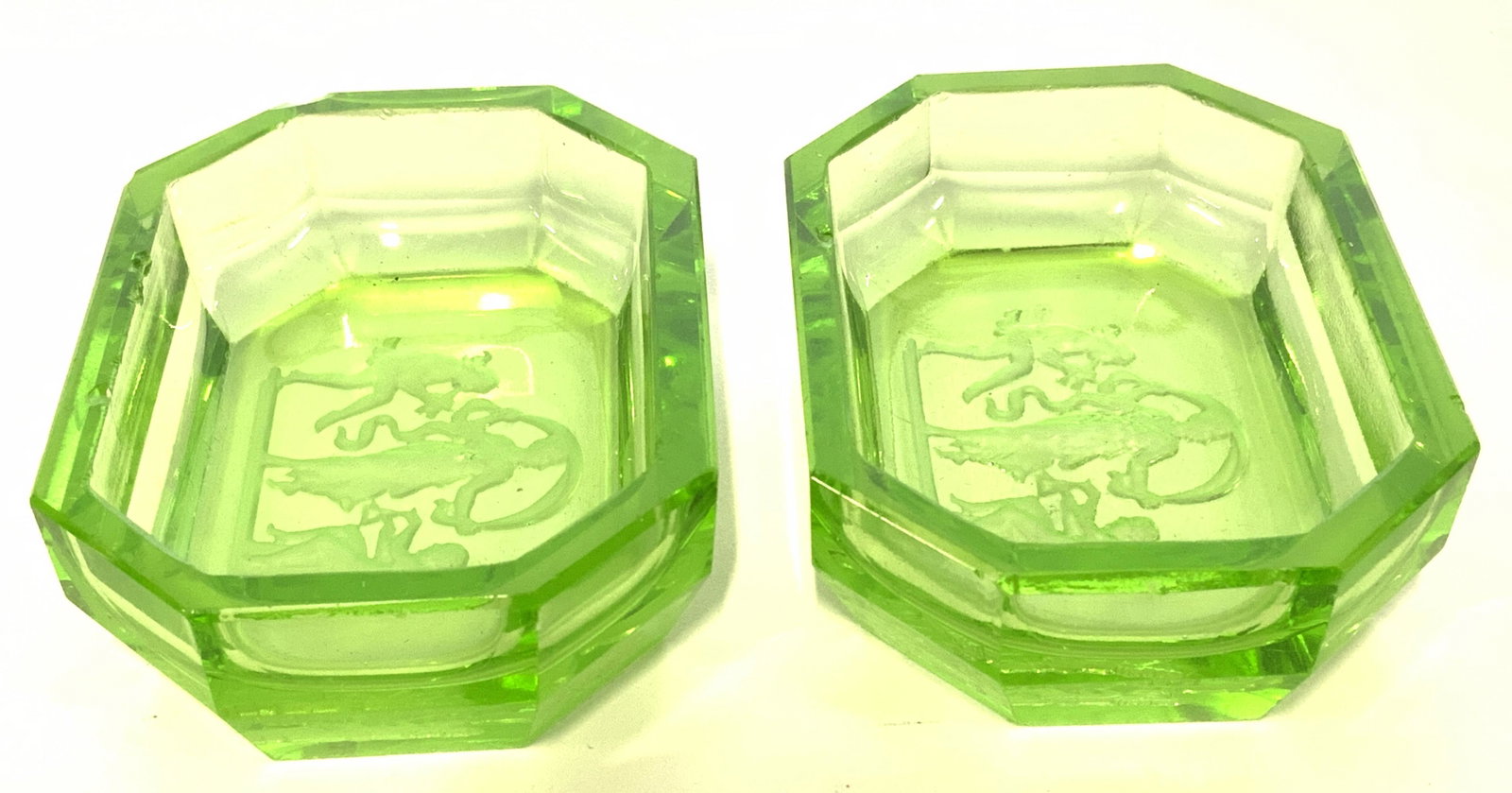 Pair Green Art Glass Salt Cellars: Undersides of salt cellars have intricate frosted relief figural detail. Pieces measures approx 2.75 inches long 2 inches wide .5 inches tall. Salt cellars, glass salt cellars, Art glass salt cellars,