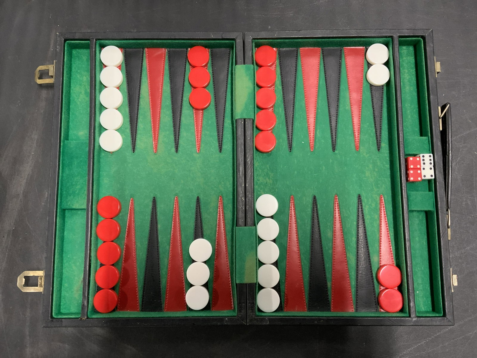 Vintage Leather Backgammon Board: Vintage, possibly antique, backgammon board. Board can be folded and act as a container for the game pieces. Exterior is leather, a handle allows for carrying. Secured shut by brass clasps. White piec