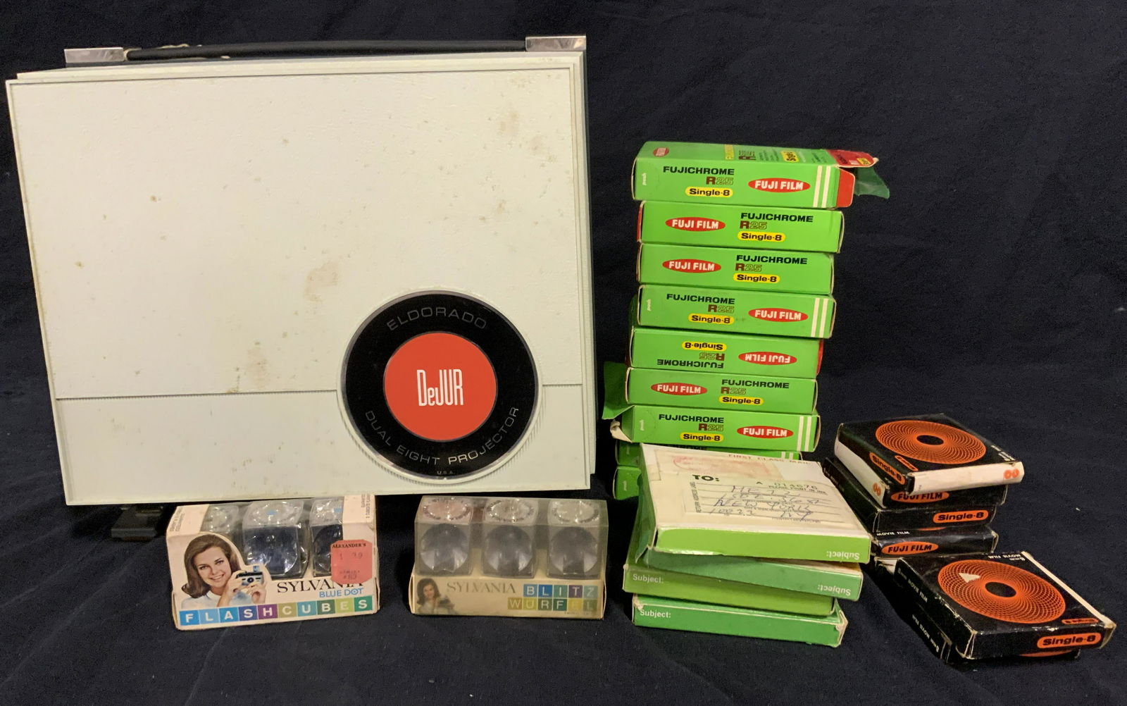 Vintage DEJUR Projector & Film Reels: Vintage DEJUR Projector, includes several reels of 8mm film. Films have not been viewed. Several films are marked with memos, others are addressed to MRS. METZ. Could include video including the royal