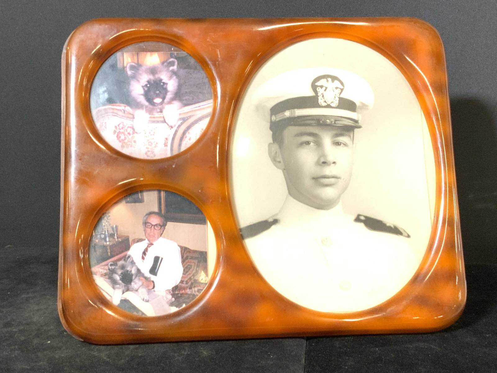 Vintage Collectible Bakelite Picture Frame: Vintage collectible Bakelite picture frame. Amber toned coloring. Rounded edges. Underside has a kickstand to keep the frame upright. Kickstand loose. Approx. 10H x 12W in. Photos in frame are both bl