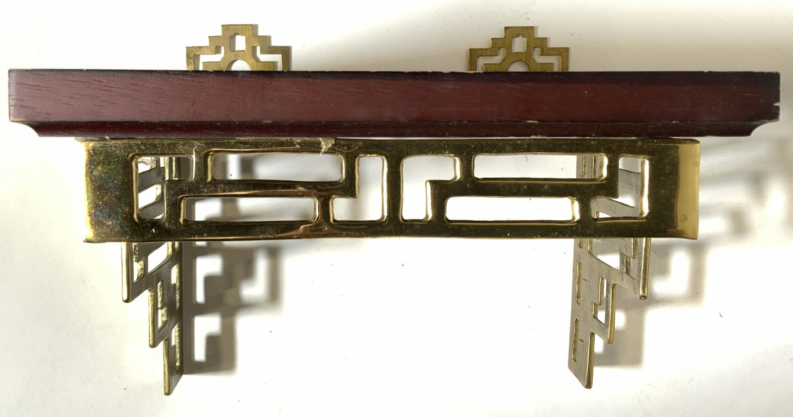 Wooden Wall Shelf W Brass Supports: Wall shelf appears to be wooden, possibly veneer. Piece has gold toned brass supports with pierced geometric detail. Shelf measures approx 7 inches tall 9 inches wide 6.5 inches deep. Wall shelf, shel