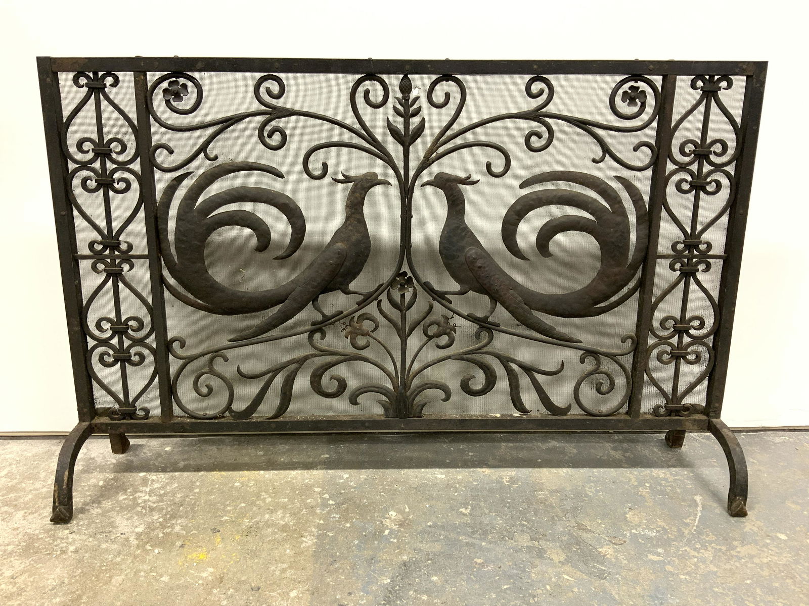 Vintage Iron Pheasant Fireplace Screen: Fireplace screen is vintage possibly antique. Screen is black toned and appears to be iron due to significant weight. Piece has pheasant structure detail on each side in addition to c, s curve, floral
