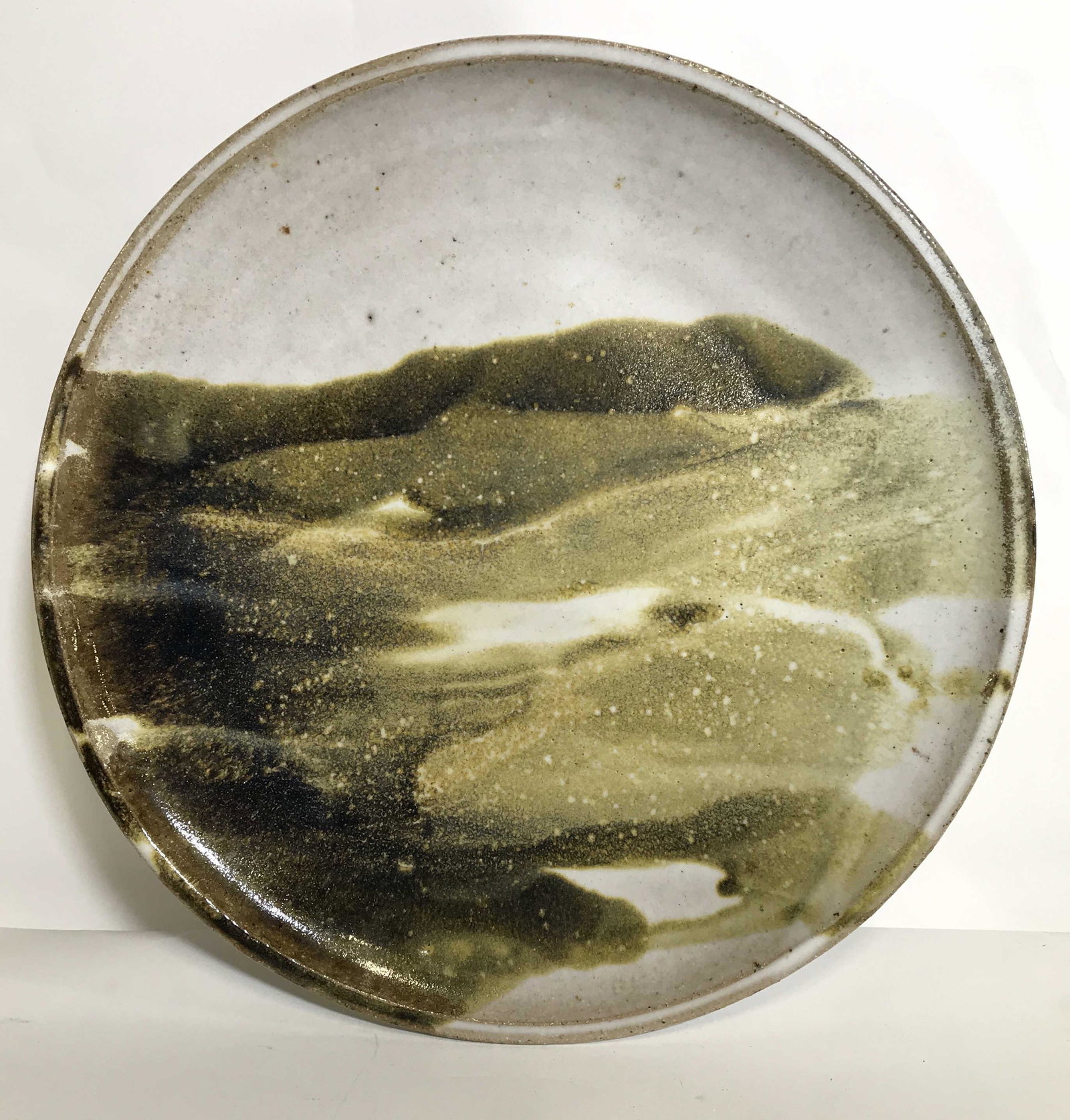 Vintage Signed Art Pottery Charger with Glaze: A vintage signed art pottery plate / charger. This piece is speckled and has a white glaze with greenish brown glaze abstract decoration. The signature is illegible. There are no apparent losses. The 