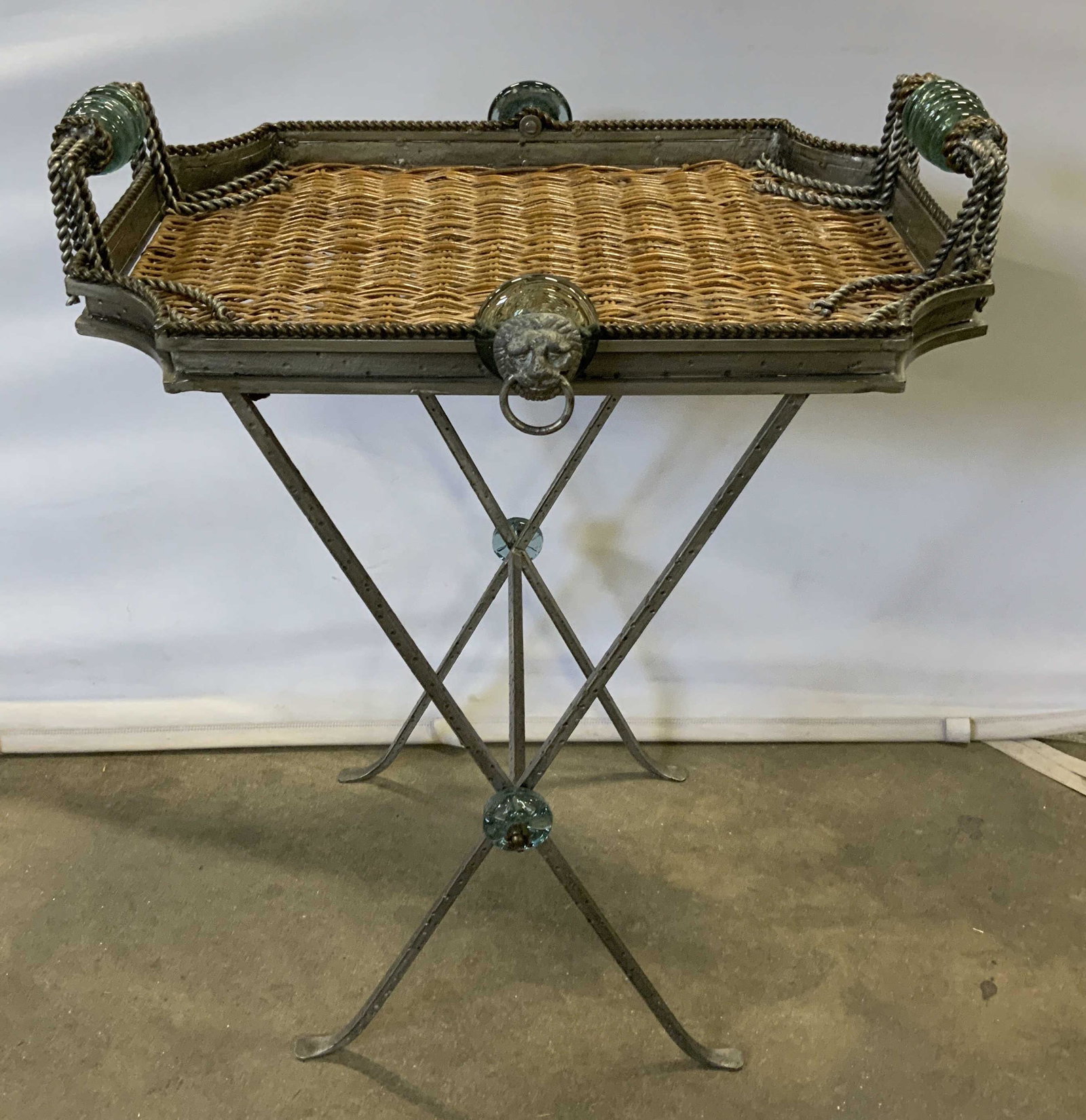 Vintage Metal & Wicker Tray Table: Vintage metal tray table. Tray is crafted from woven wicker and metal. Lion heads decorate each opposite sides of the trays. Handles are crafted from glass. Legs are collapsible and tray is removable.