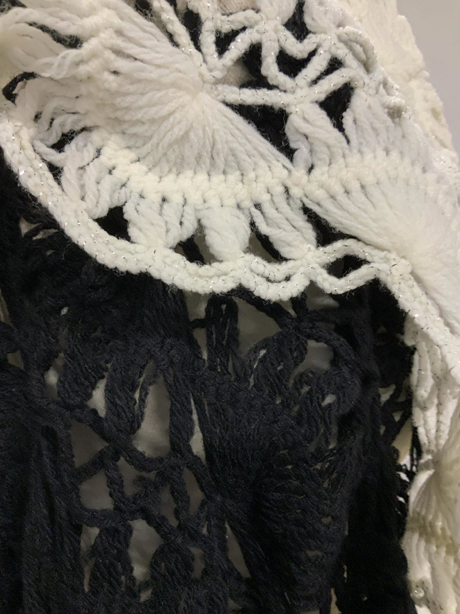 Lot 3, STEVE MADDEN & Handmade Shawls: Fashion Label Steve Madden Black Acrylic Knit Triangular Shawl with tassels. One size. 60 in at widest. 26 in long. Two hand knit wool shawls with end tassels, one in black, one off white with silver