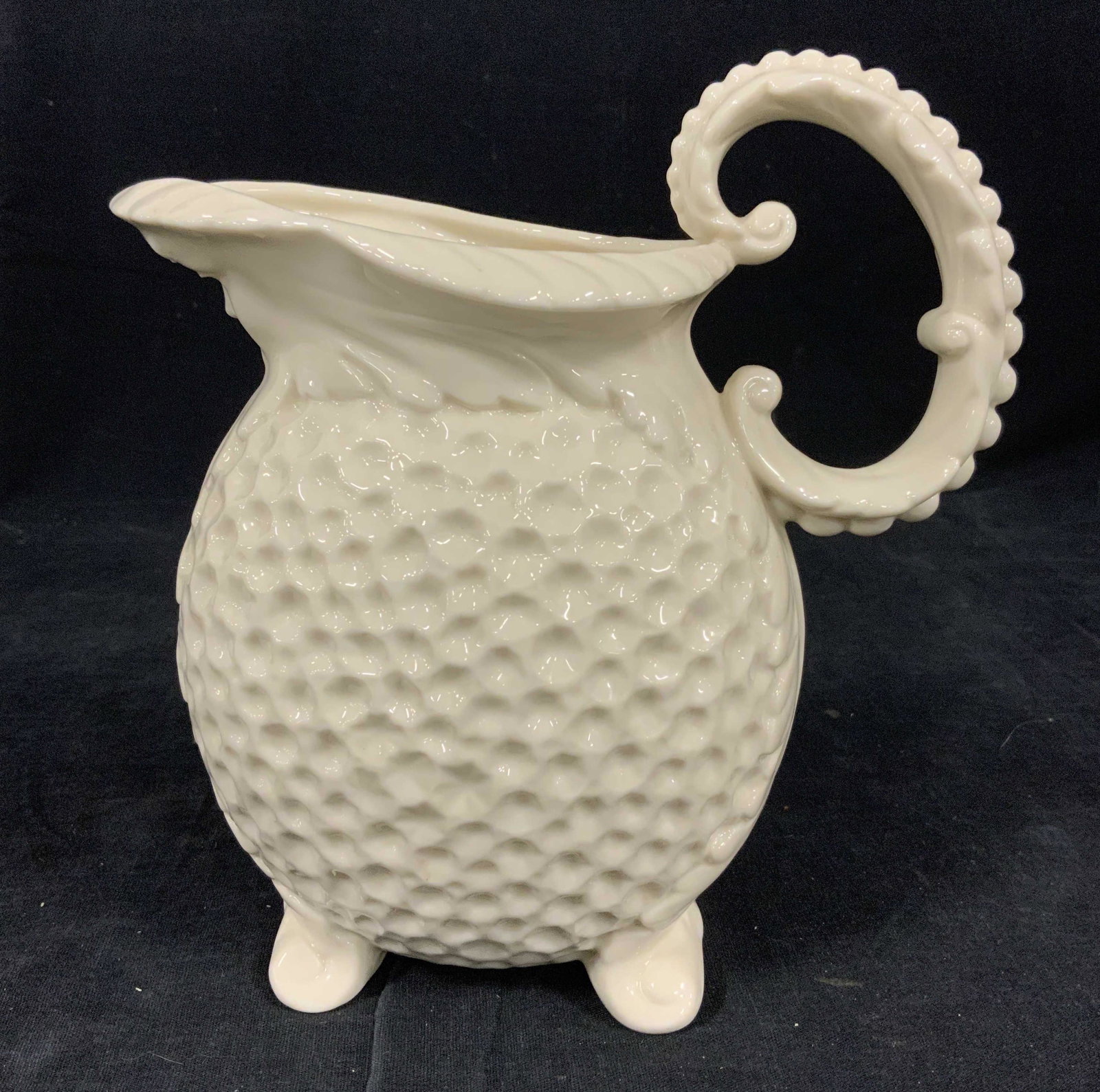 LENOX Footed Ceramic Pitcher: LENOX footed ceramic pitcher, possibly vintage. Body of pitcher is cratered, handle resembles a leaf, leaf like detailing runs along pitcher back, a woman’s face is cast beneath the spout. Measures 