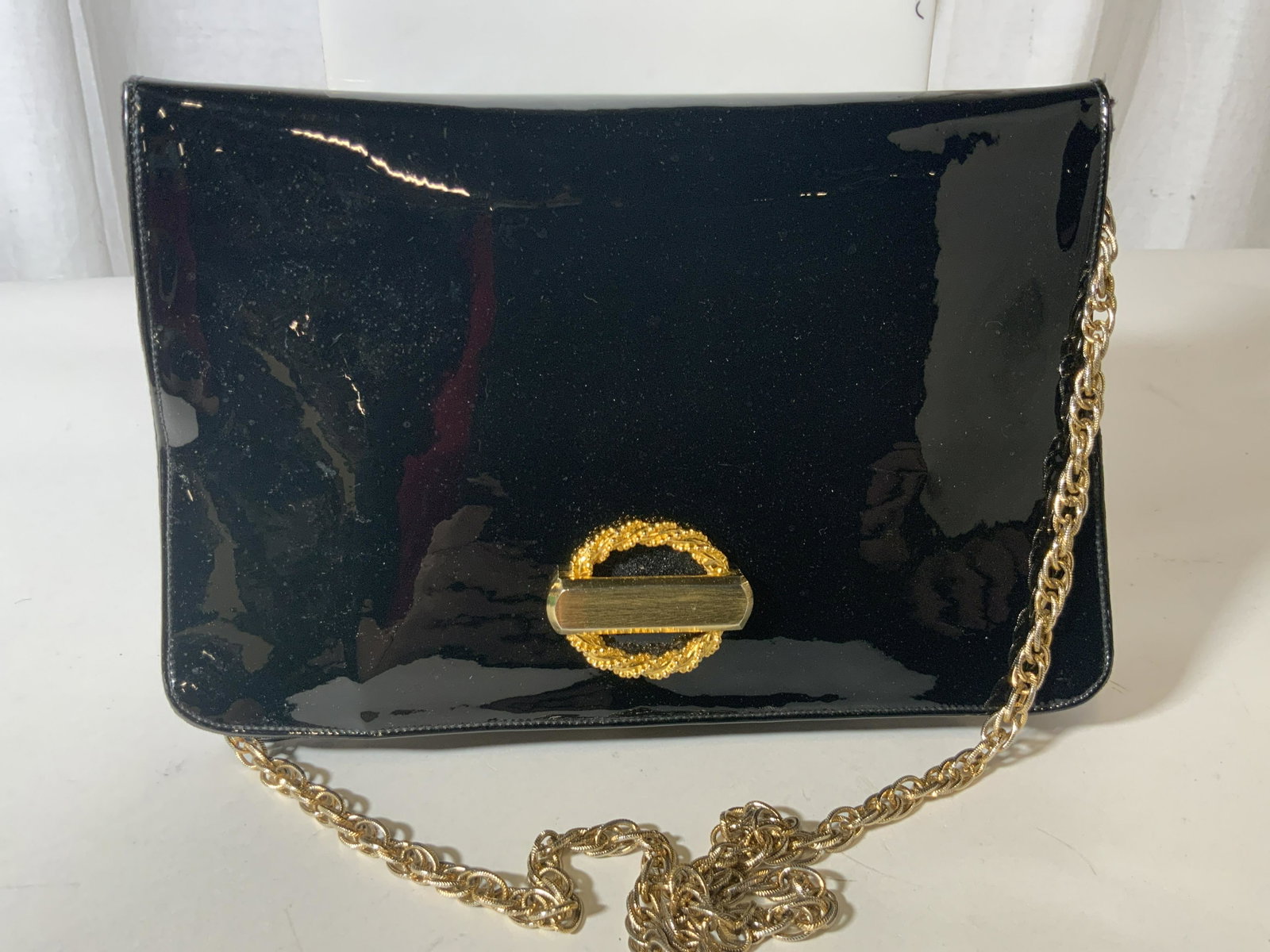Saks Fifth Avenue Patent Leather Style Bag/ Clutch: Black patent leather style luxury brand purse with gold tone accessories, including multi link diamond cut chain. Drop is 14 in. Bag 9.5 x 6 in. Fabric lining with original luxury label. Patent leathe