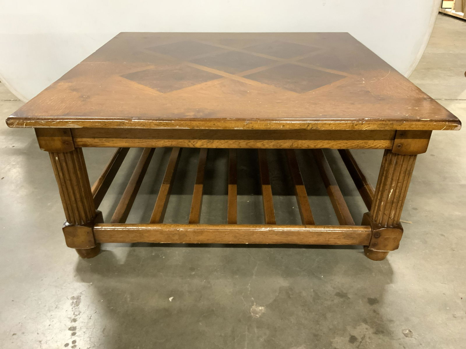 MILLING ROAD HILDEBRAN Wooden Coffee Table: Underside has tag which reads MILLING ROAD HILDEBRAN MADE IN ITALY. Coffee table is square shaped and wooden. Piece has carved wooden legs with stretchers in between. Piece measures approx 42 inches s