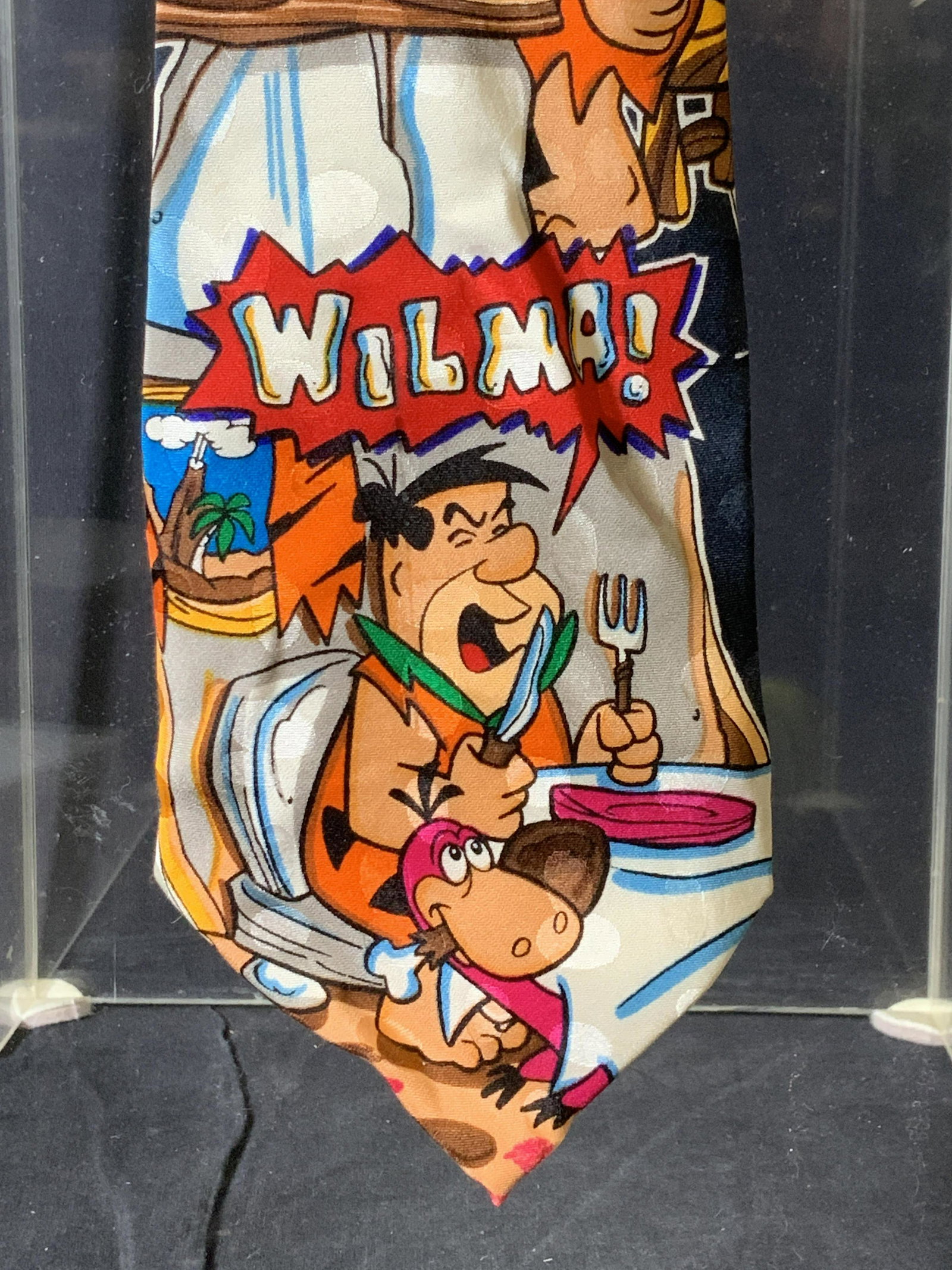 FRED FLINTSTONE ‘Wilma’ Silk Fashion Tie: Hanna Barbers c. 1993 Fred Flintstone Tie. 100% silk, Cartoon character FRED FLINTSTONE screaming ‘WILMA, WILMA WILMA’ Also features Dino character. Total length 59.5 in. Width 3.75 in. Vintage Ca