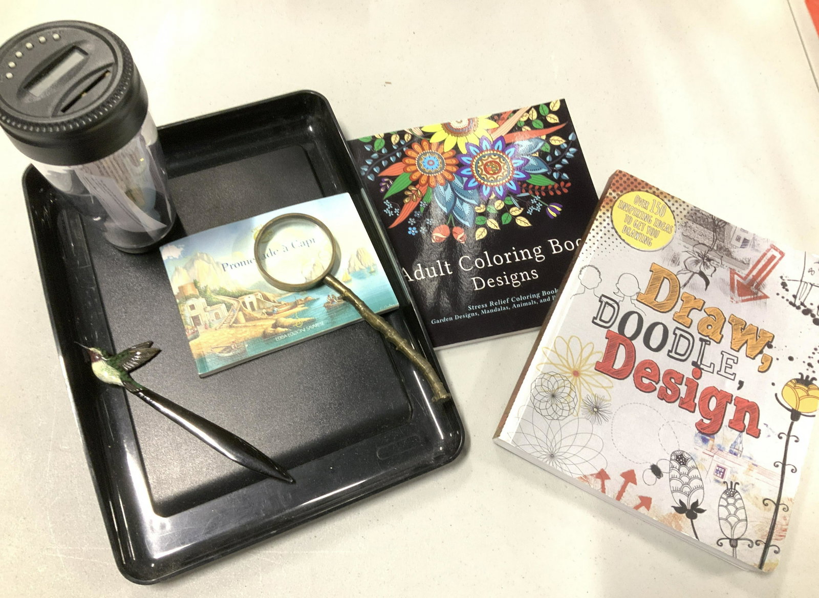 Lot 7:Creative Desktop Accessories, Coloring Books: Desktop Accessories for adults and for kids. Lot includes paper tray, battery operated digital money bank with instructions, hummingbird letter opener, bronze magnifier, mandala & animal coloring book