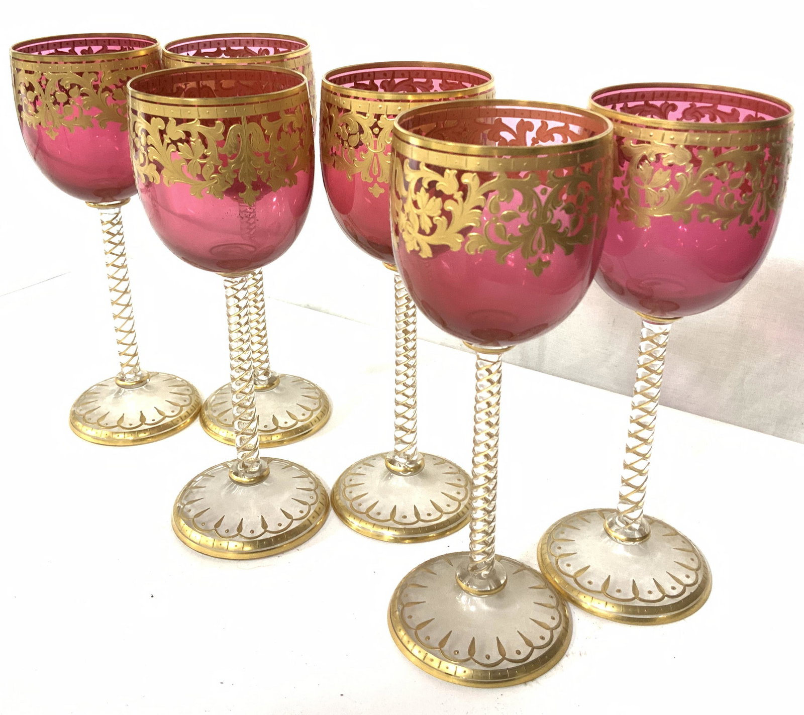 6 Cranberry & Gilt Crystal Vntg Bohemian Stemware: Set includes 6 goblets with quality solid gilt on European Art Nouveau scroll pattern. Continues from cranberry down twisted stem to base. 7 in. Ht, 2 in. diameter. Vintage Bohemian Stemware, cranberr