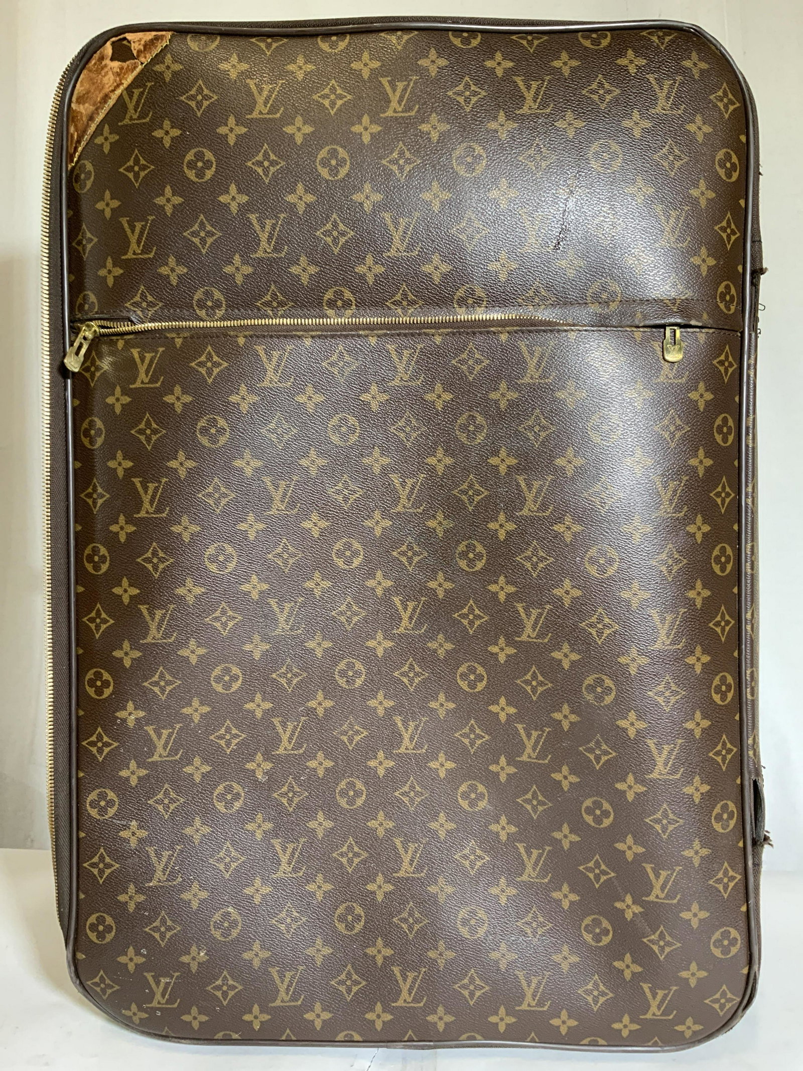 In The Style Of LOUIS VUITTON Wheeled Luggage: Luggage is marked LOUIS VUITTON on gold toned accent areas on top of handles. Piece is in the style of LOUIS VUITTON. Luggage is brown with gold toned LV & geometric pattern. Piece has adjustable hand