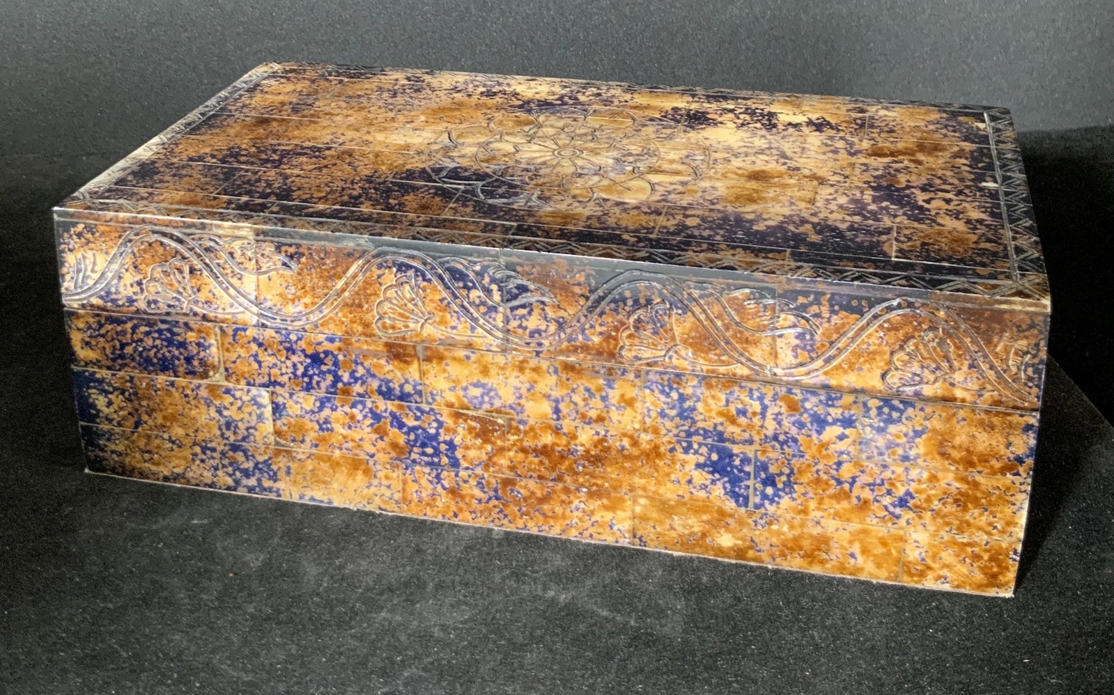Vintage Carved Bone & Wood Lidded Keepsake Box: Vintage carved bone tile and wood rectangular lidded trinket box. The exterior features blue, brown, purple, and black hues throughout. The colors are splashed together to create a unique design. The 