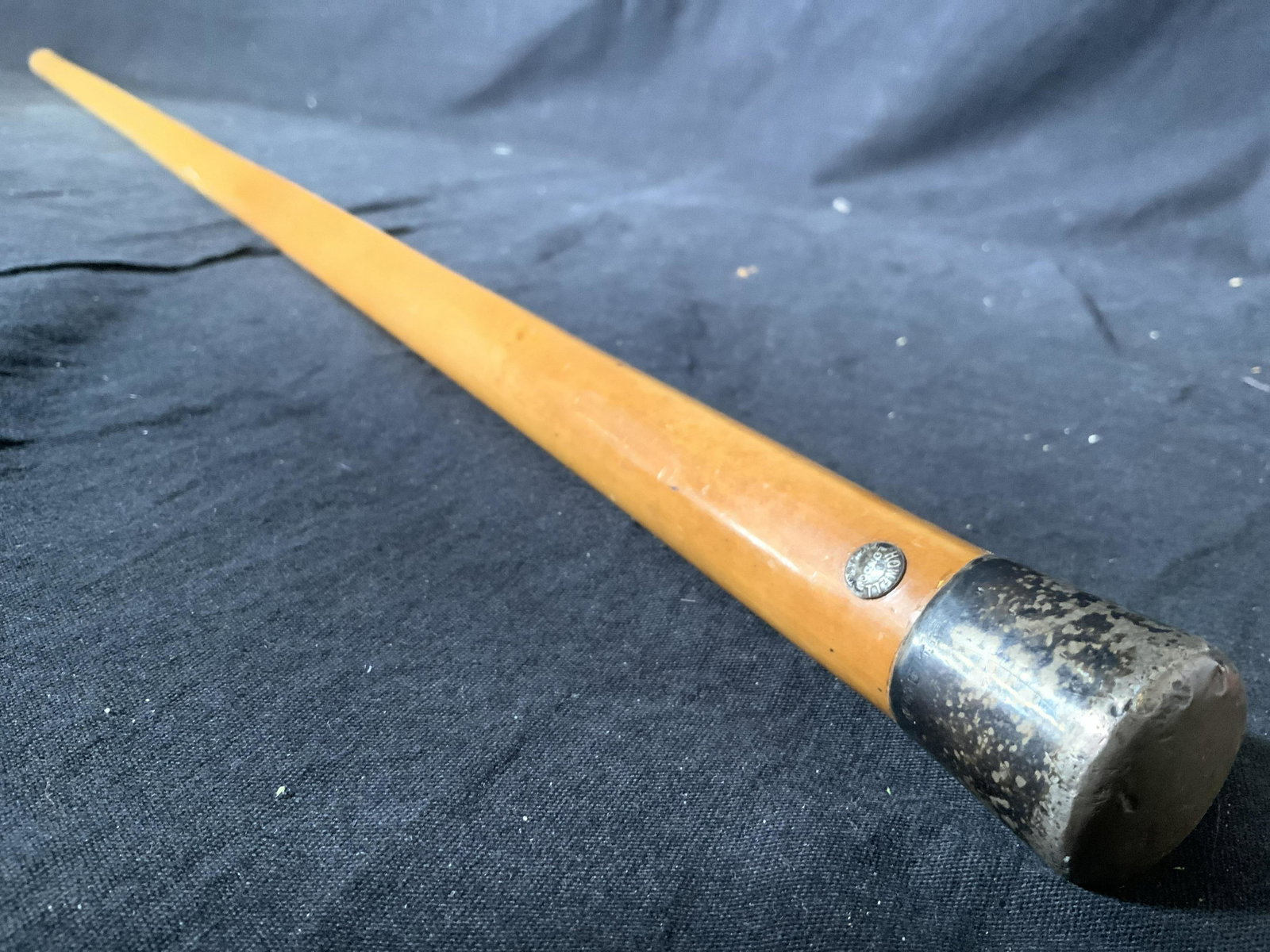 HOWELL LONDON Wood & Metal Cane: Button near top reads HOWELL LONDON. Piece appears to be vintage. Cane is wooden while top of cane is metal, possibly silver plated with illegible trademark. Cane measures approx 35 inches tall 1.25 i