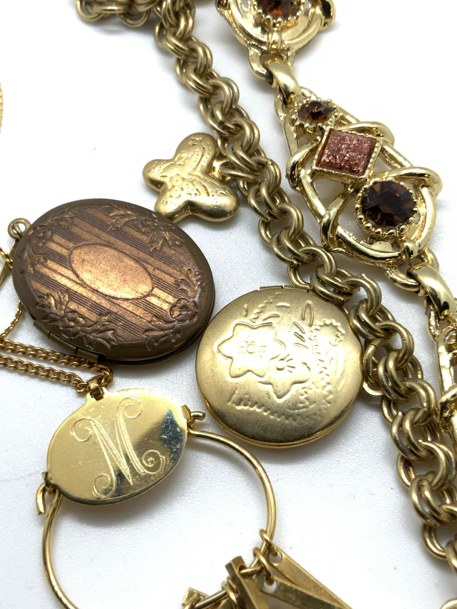 Lot 4 AVON & More Locket Bracelets & Necklaces: Four gold tone metal accessories that can be worn together or separately. One gold tone chain bracelet decorated with three locket charms; a heart, a circle, a oval. Each locket charm features etched