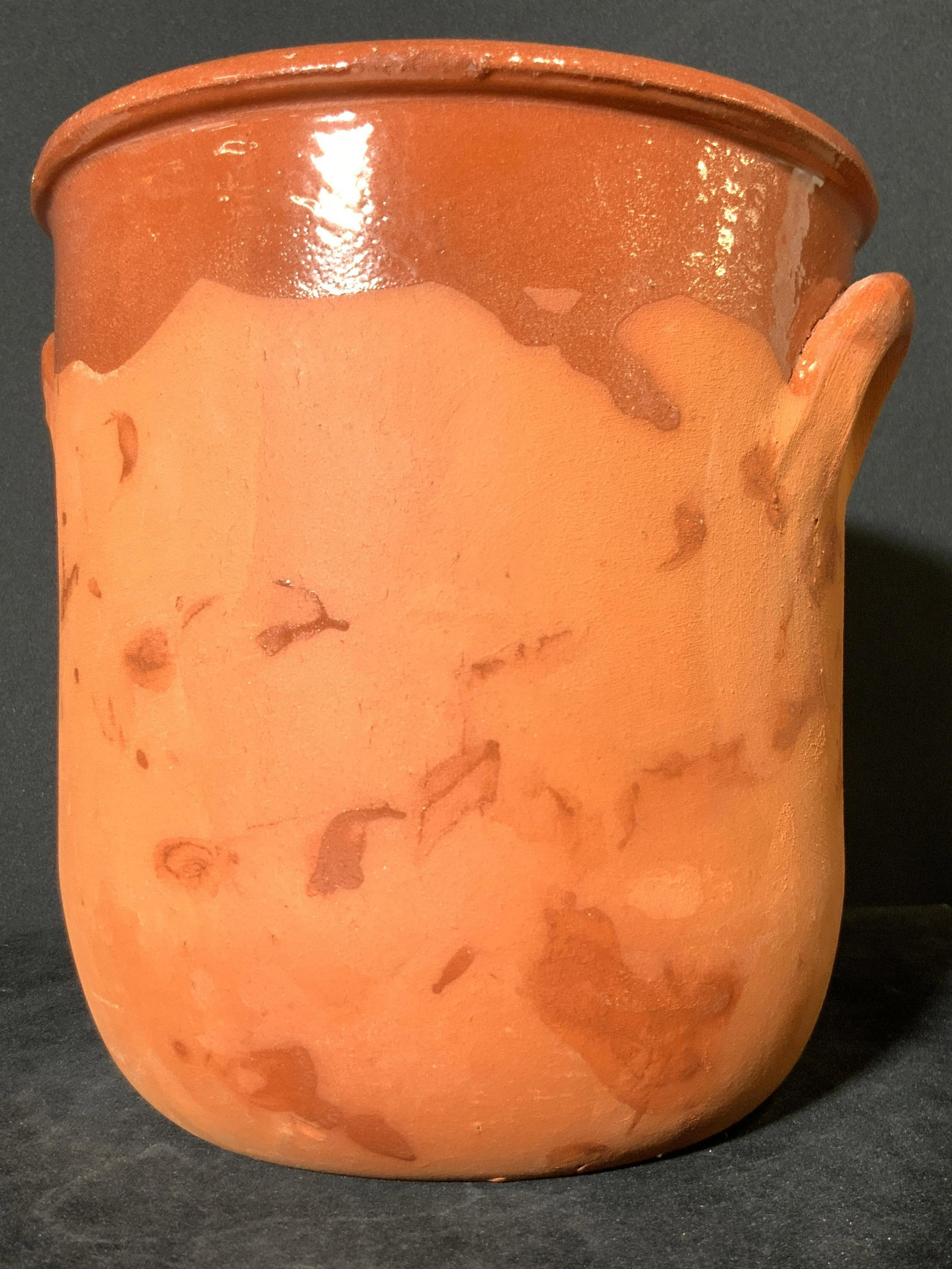 Vintage Handmade Artisan Ceramic Cachepot: A vintage orange hued half glazed ceramic cachepot. Comprised of thick walled ceramics. Slightly Weighty. Twin handle accents on either side. Interior is fully glazed. Approx. Height 7 in. Approx. Wid