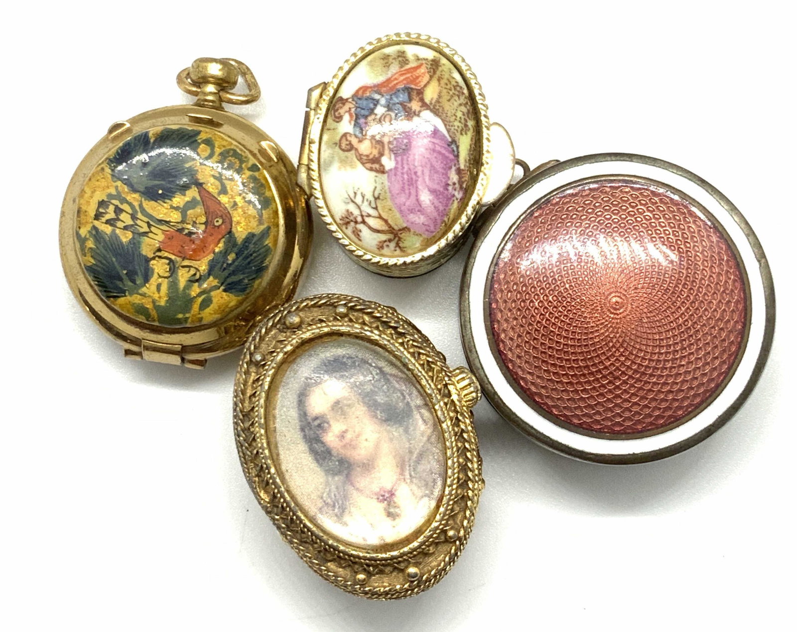 Lot 4 Antique ENAMEL & GUILLOCHE Pill Boxes: Four antique and vintage pill boxes. One features a hand painted ceramic lid depicting a man and a woman sitting in a nature scene. The piece is crafted from gold tone metal and features intricate etc